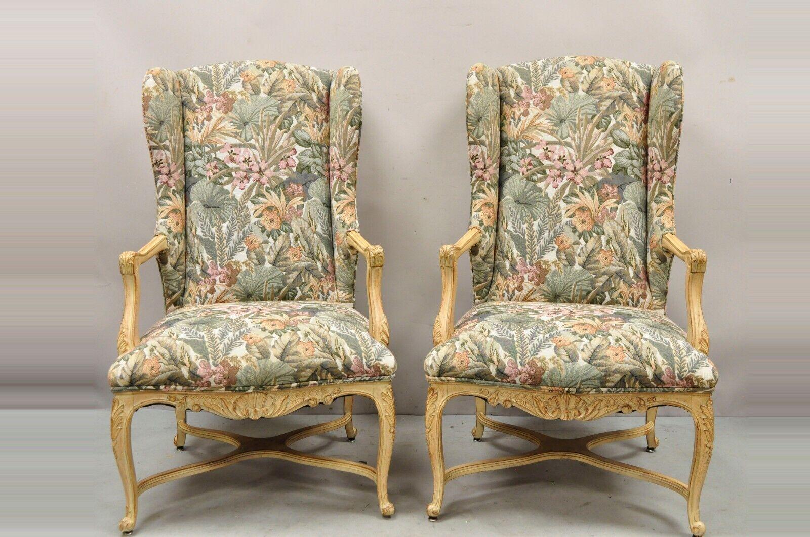 Pair of French Provincial Country Louis XV Style Upholstered Wingback Lounge Chairs Item features a white washed distressed finish, shapely winged backs, cross stretcher base, floral print upholstery, nicely carved details, cabriole legs, quality
