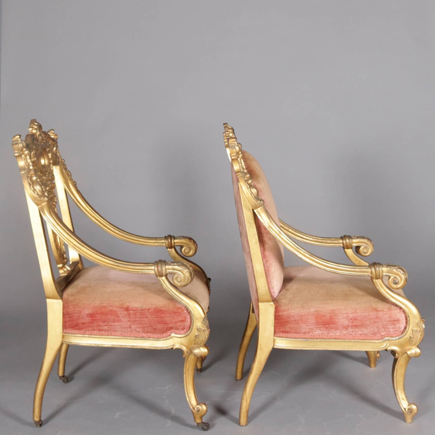 Pair of French Rococo style giltwood armchairs feature pierced foliate and scroll carved crests, scroll form arms and legs, velvet upholstered seats, and one with open ribbon back and the other with upholstered back, circa 1880

Measures: hollow