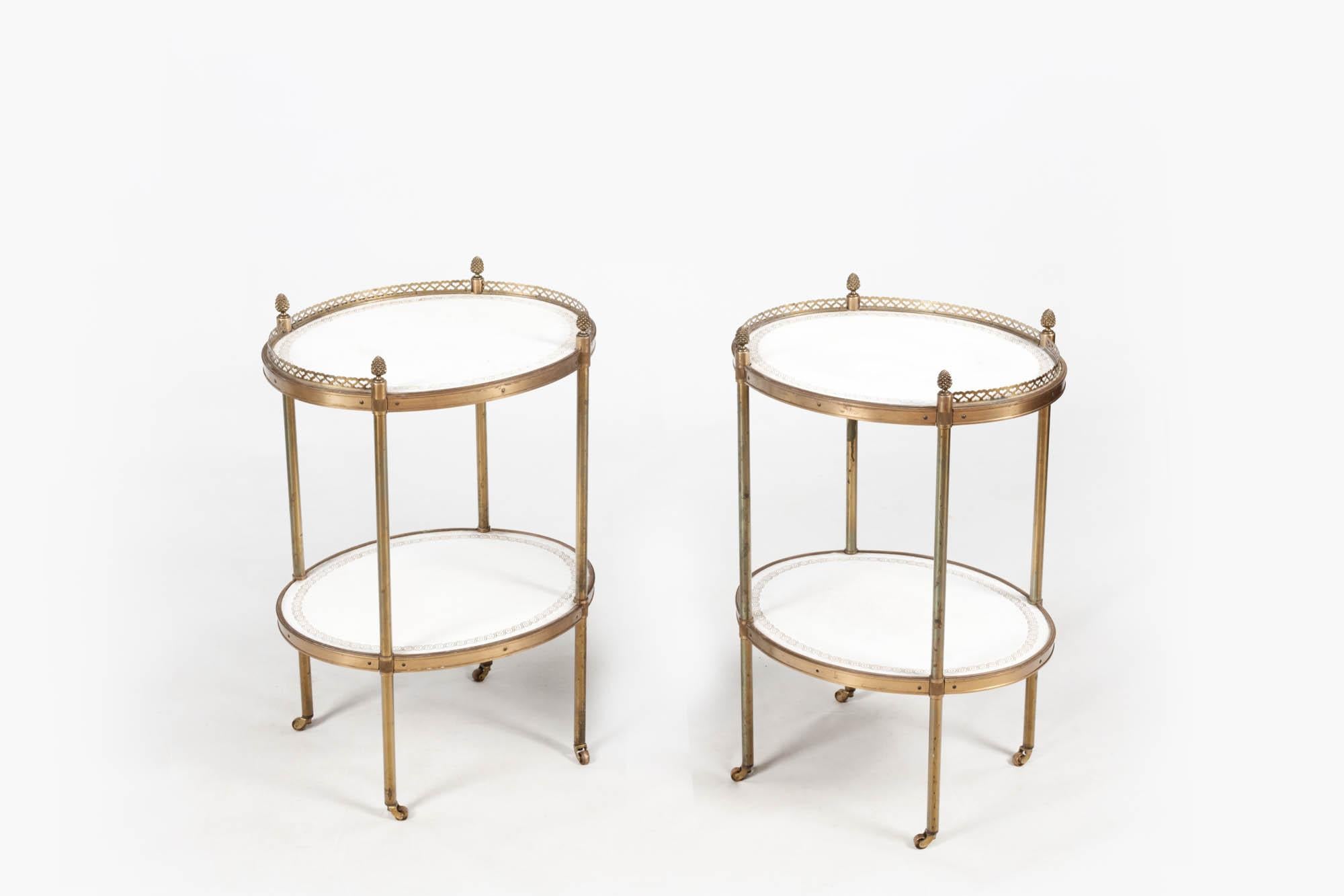 Pair of French-style 19th-century petite end tables in the manner of Maison Jansen with brass filigree ribbed edging and acorn finials. Both have tooled cream leather tops and shelves below with the legs terminating on simple castors.