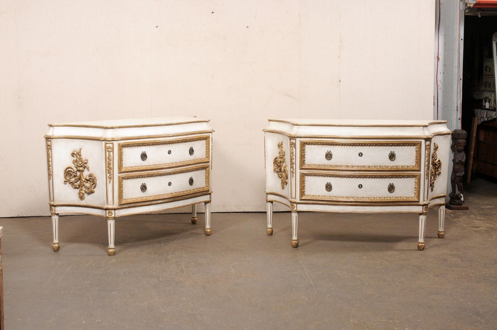 Paire de commodes surélevées à deux tiroirs de style français, de belle taille, en blanc avec des accents dorés. Ces coffres vintage ont été fabriqués en Amérique et leur design s'inspire du style néoclassique français. Ils ont tous un corps