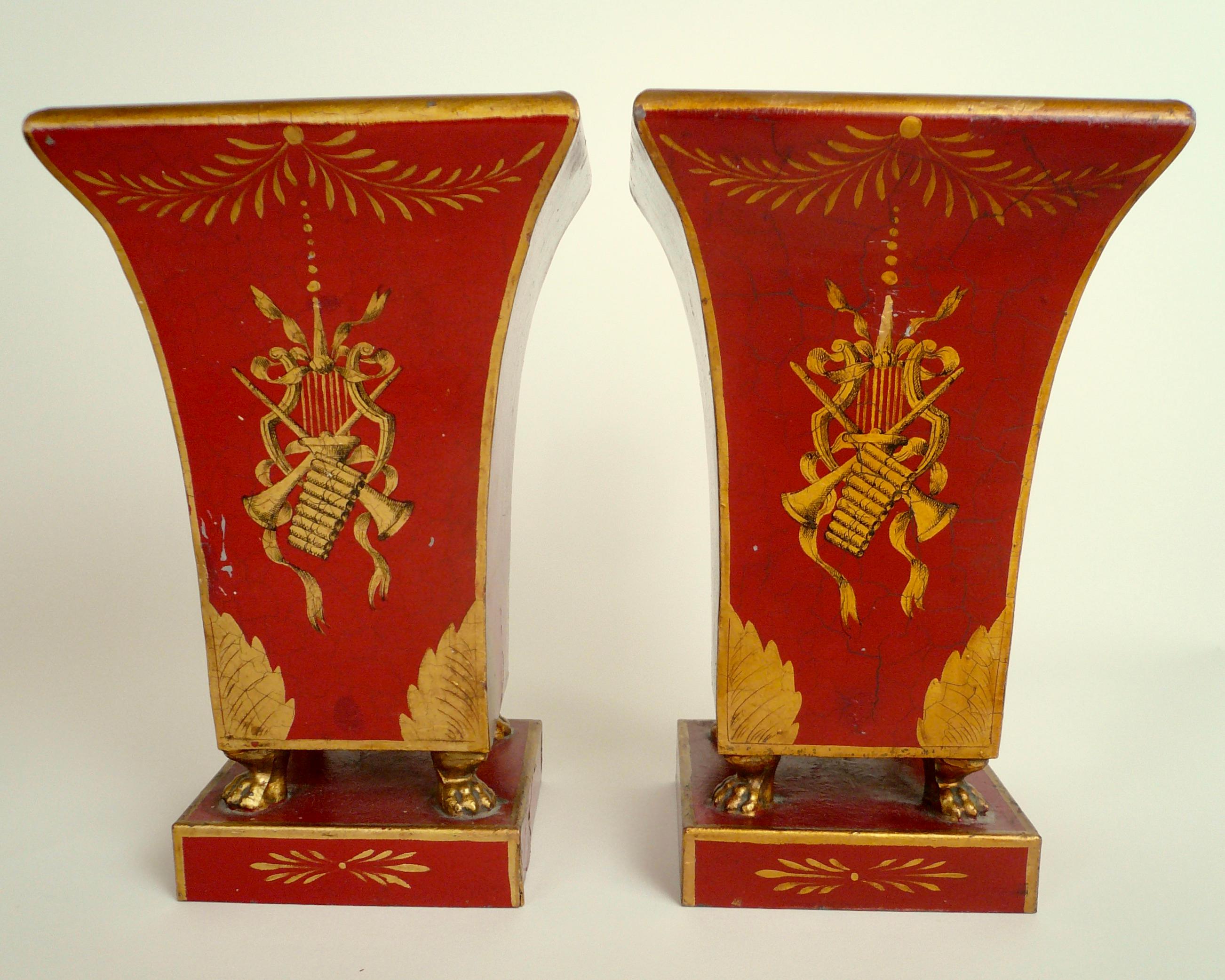 Dieses hübsche Urnenpaar ist mit vergoldeten klassischen Motiven wie Musiktrophäen und Tatzenfüßen verziert.