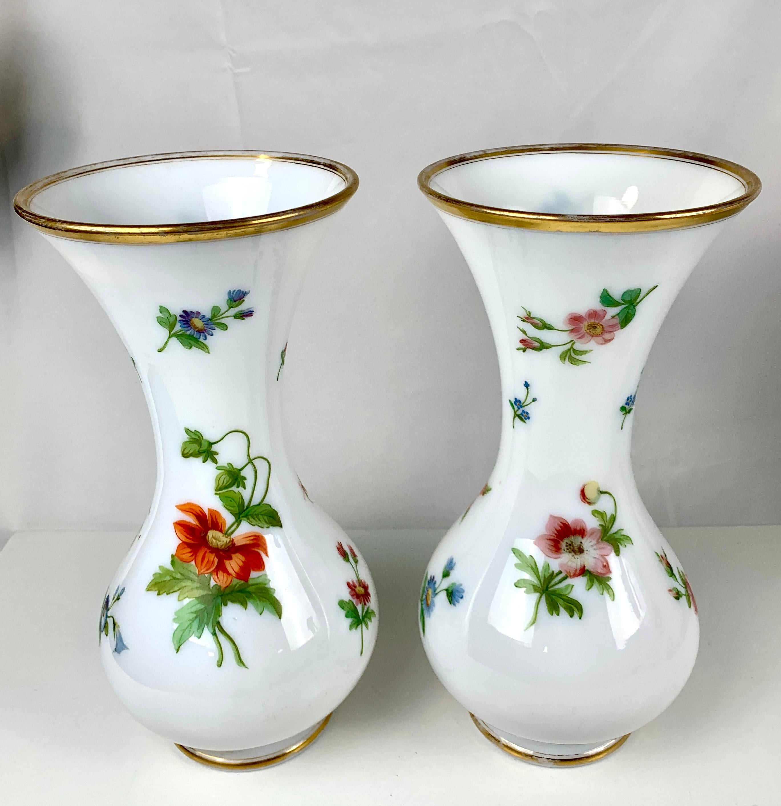 Pair of vases with hand-painted flowers on opaline glass. 
We see pink, purple, orange, lilac, and white flowers, all naturalistically rendered.
The roses, daisies, and morning glory are marvelous!
The leaves are painted in several shades of
