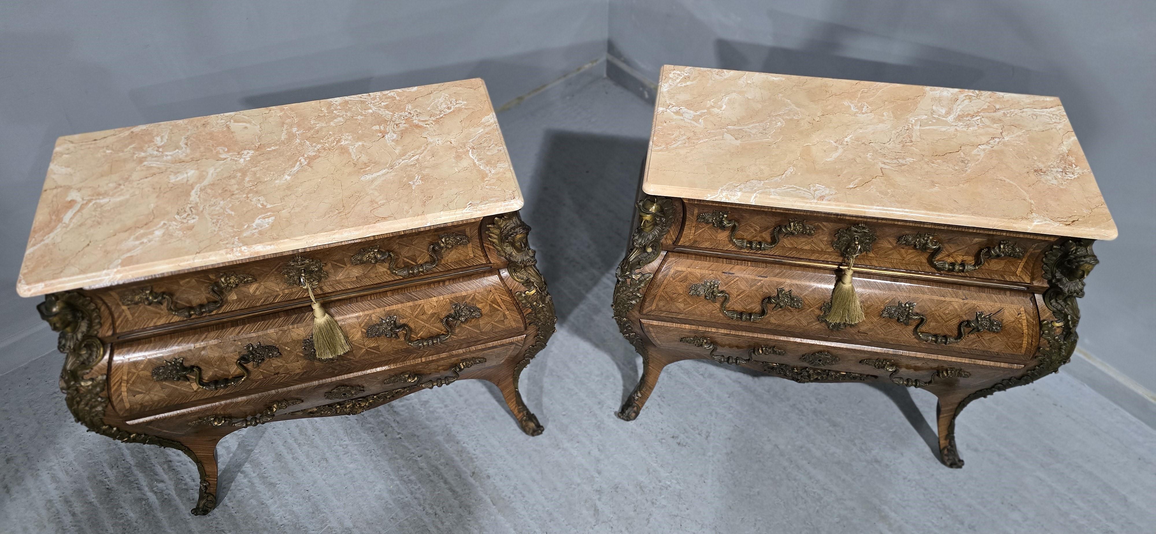 Espléndida pareja de cómodas francesas de estilo Luis XV en forma de parquet de versalles de tres cajones de pequeñas proporciones, con monturas de bronce dorado ormolu en forma de hermas masculino y femenino, y tiradores y escudos de vides