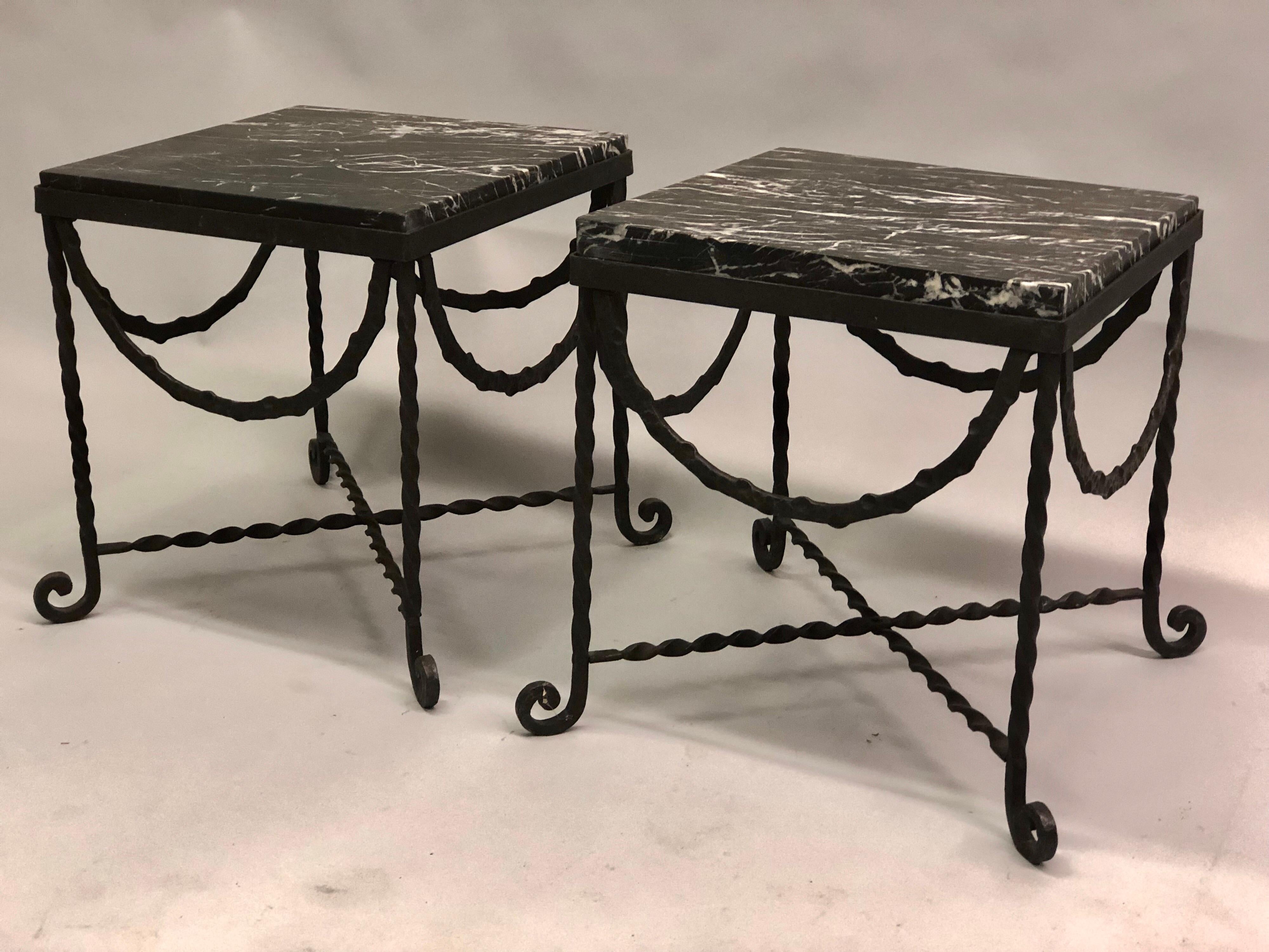 Pair of French midcentury / Art Deco wrought iron and black marble side or end tables attributed to Edgar Brandt, circa 1925-1930. The pieces can also be used together to form a coffee table.

The tables are hand hammered in iron using a twist