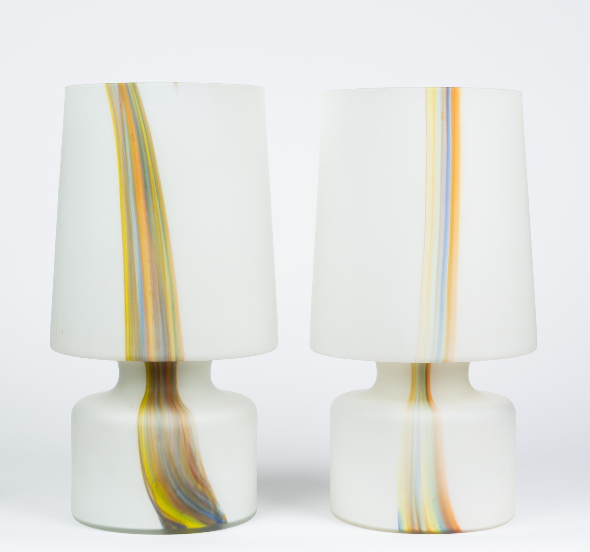 A pair of tall frosted glass lamps from Laurel Lamp Co. Constructed in the shape of a more traditional lamp vessel and detached drum shade, the piece is actually rendered from a single piece of frosted glass. The glass incorporates a ribbon of