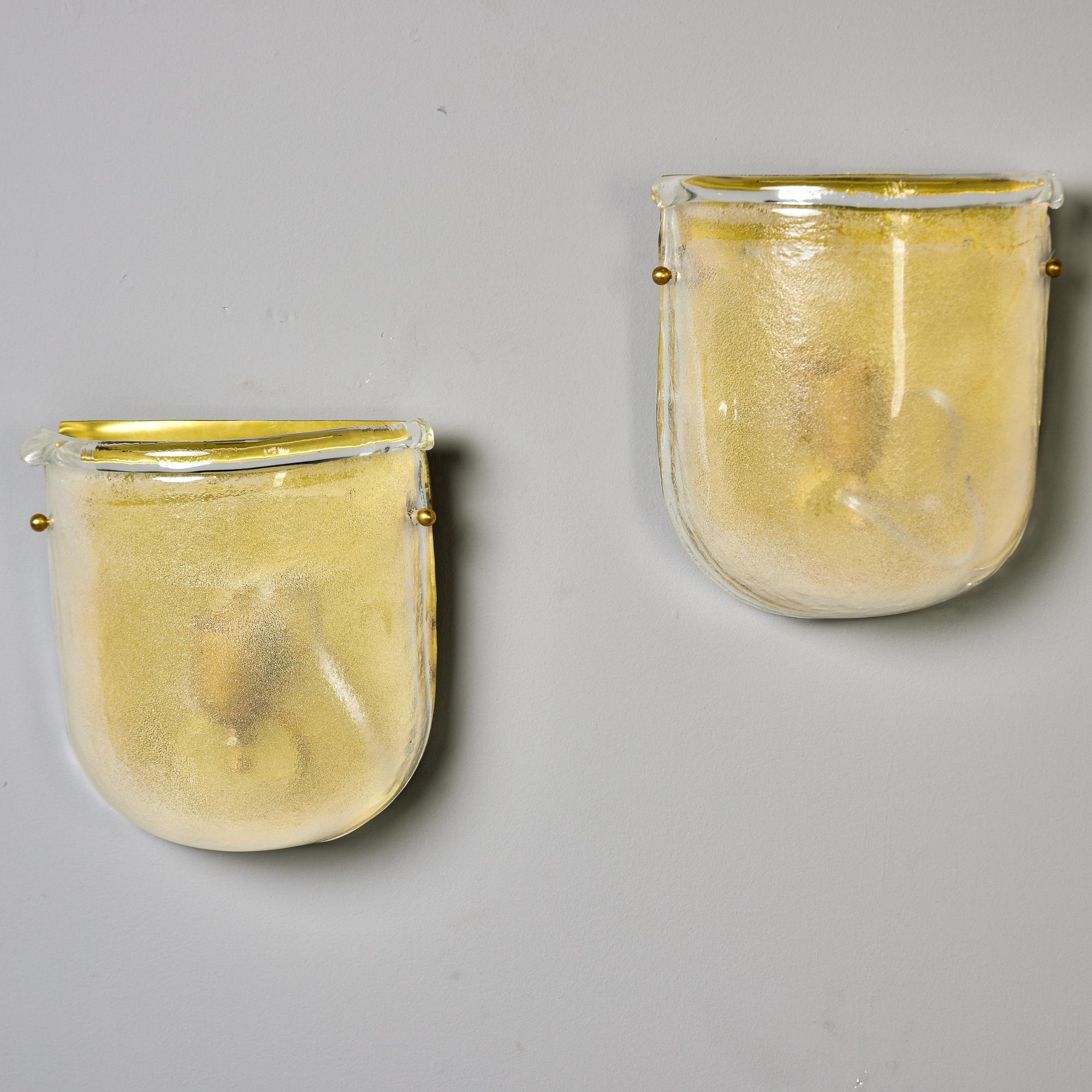 Realizzata in Italia, questa coppia di applique in vetro di Murano è caratterizzata da una forma a U con ferramenta in ottone. Ogni applique è alta più di 9 pollici, con vetro di Murano giallo pallido trattato con un lavaggio acido all'interno che