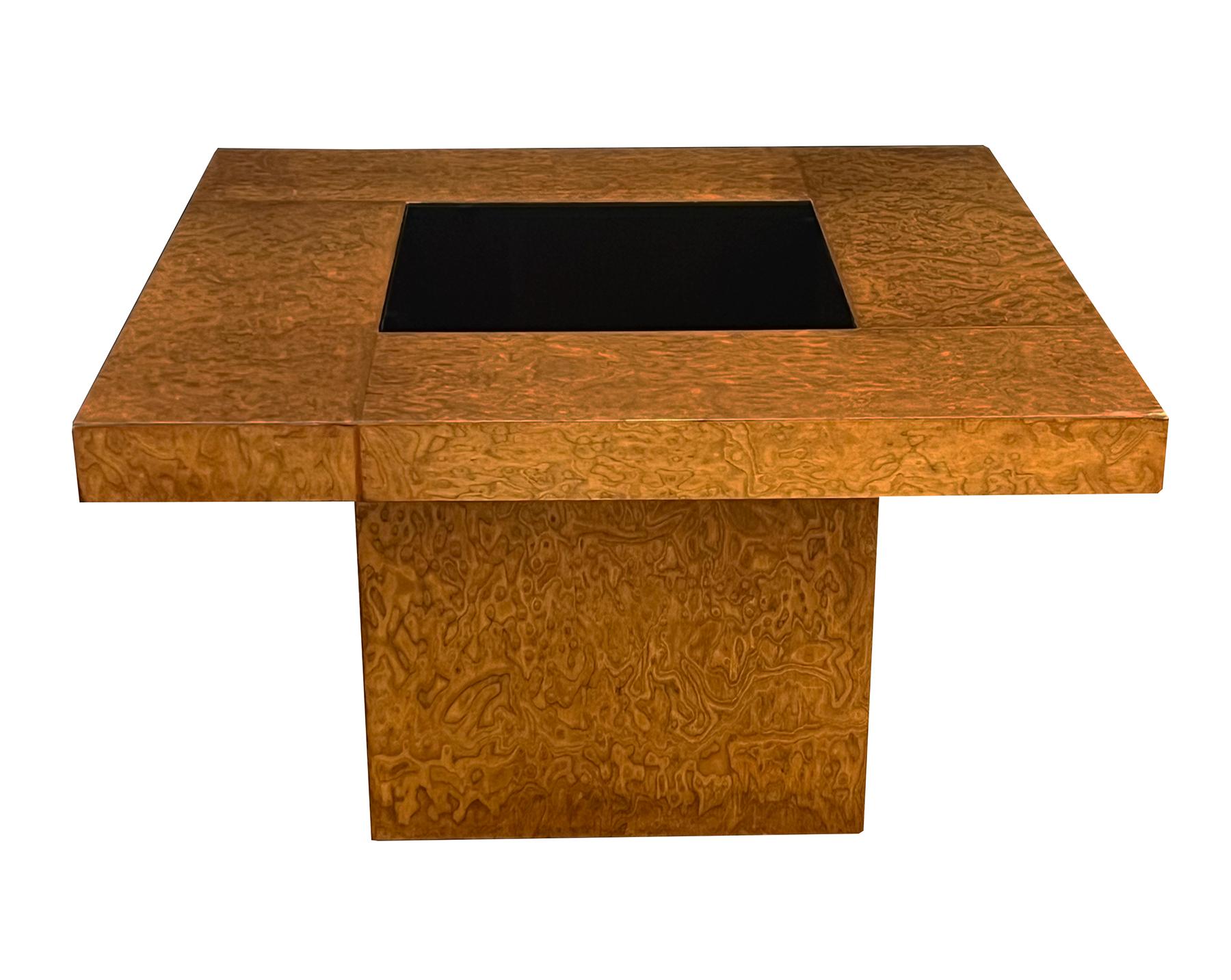 Each having a square-form top with bronze shaded glass inserts covering a mahogany-lined open well; all raised on block plinths; veneered overall in a warmly patinated and well-figured amboyna burl, one of the most expensive and sought-after of all