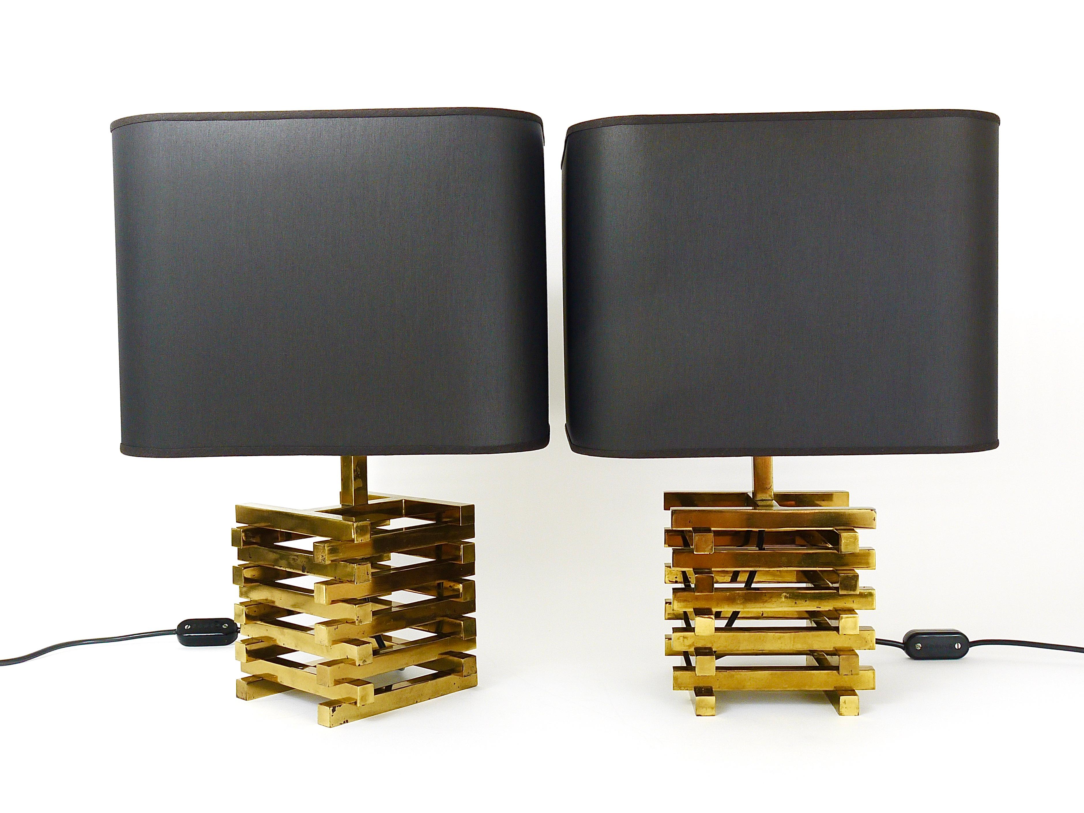A pair of hollywood regency brass table / side lamps from the 1970s, in the style of Romeo Rega, Italy. The lamps consist of beautiful and solid square brass cage bases with black refurbished lampshades. In good condition with charming patina on the