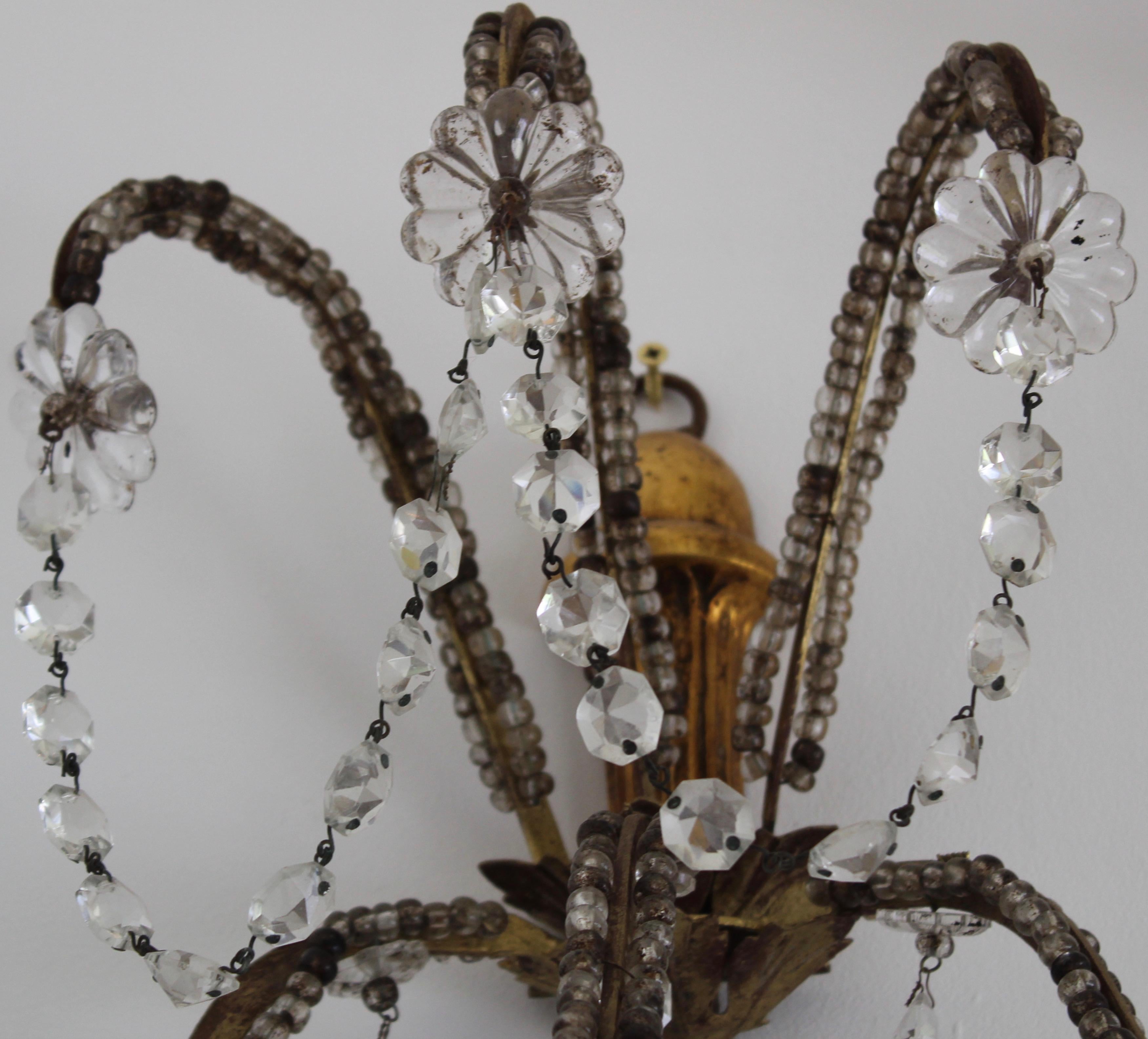 Pair of unwired beaded glass wall sconces, on a large open giltwood frame, with a carved gilt finial at the base, from which emerge 5 arms finished with candleholders. The frame extending and curving upwards with strands of glass beading along the