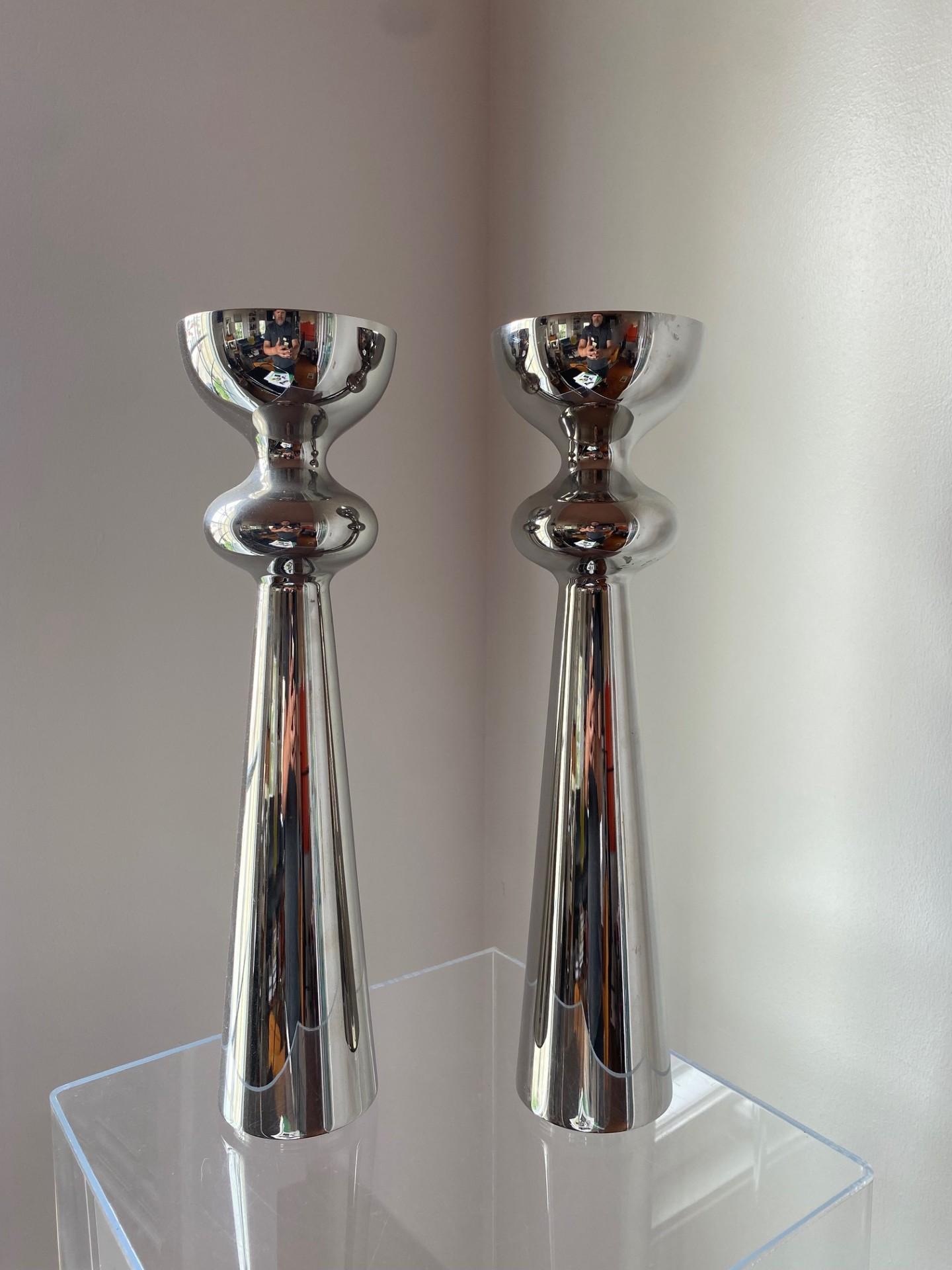 Incredibly sculptural pair of polished stainless steel vases by Georg Jensen.  This pair stands alone by themselves with their beauty.  The substantial height combined with the chrome finish radiate a minimalist radiant glow in any space that holds