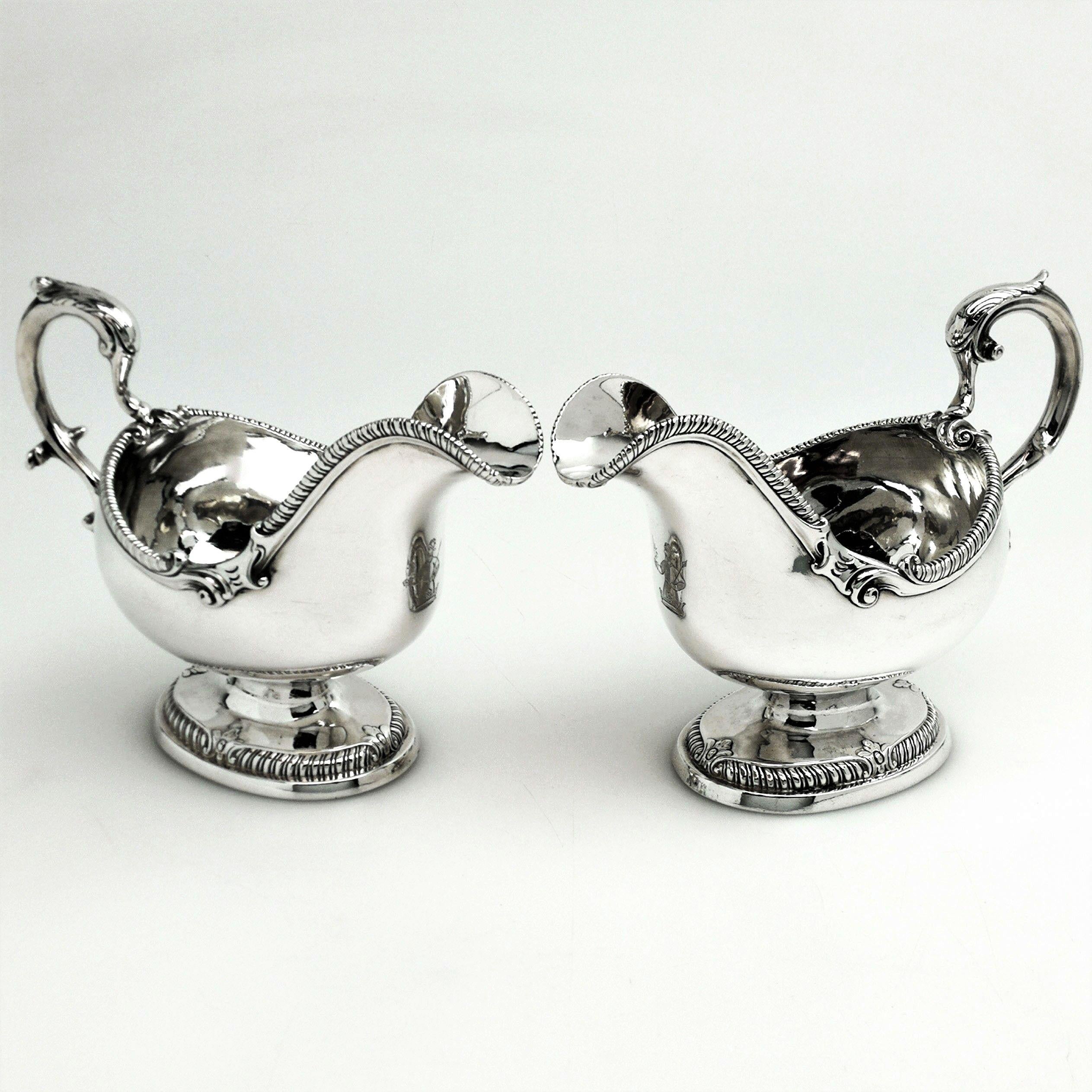 A pair of Antique George III sterling Silver Sauce Boats in a Classic Regency style design. These Sauce Boats have an oval form and each stands on an oval pedestal foot. The rim and foot of each Gravy Boat are embellished with a gadroon pattern