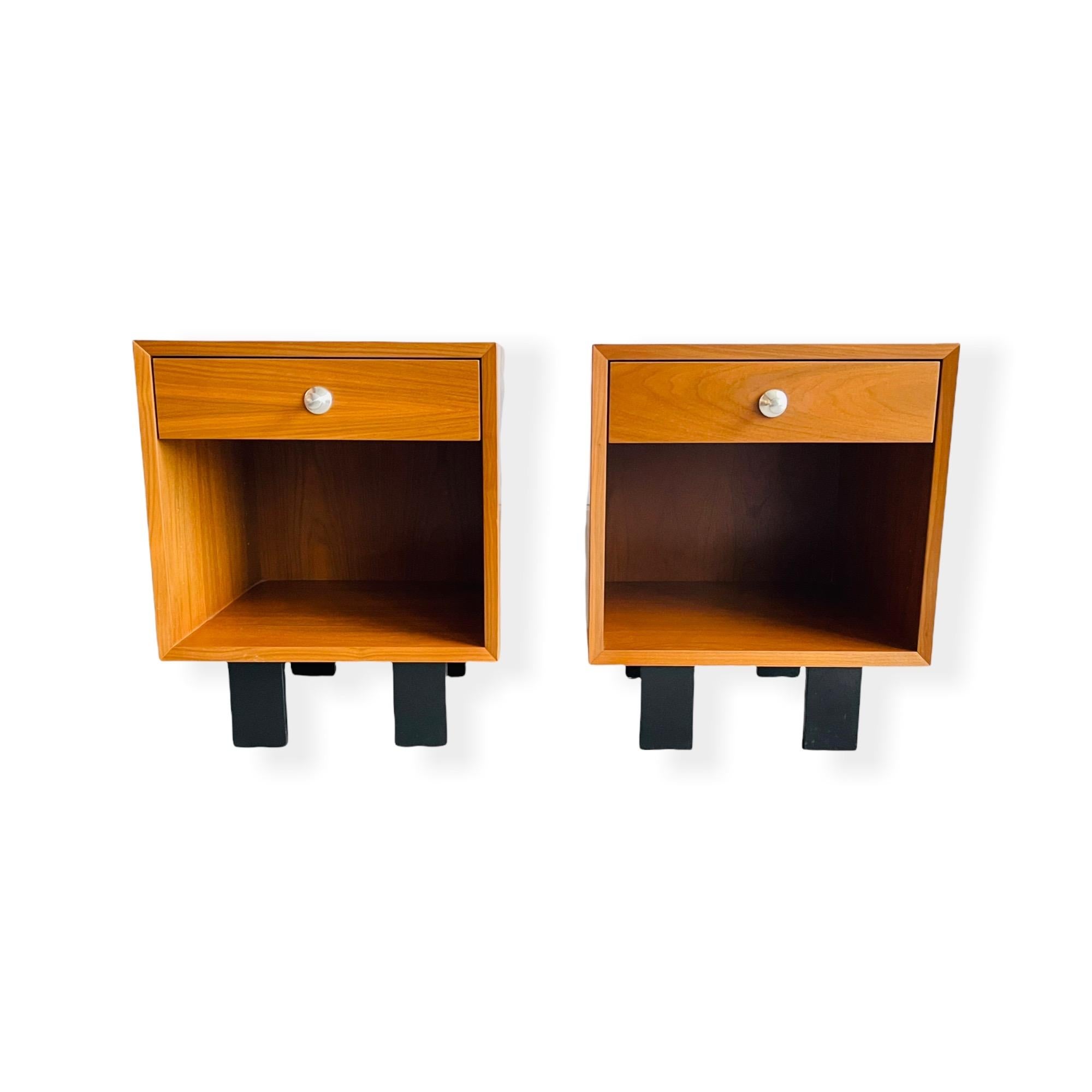 Here is a stunning pair of Mid Century Modern walnut nightstands designed by George Nelson for Herman Miller circa 1950s. These nightstands features a single smooth drawer, storage space below and black lacquered feet. The nightstands are labeled