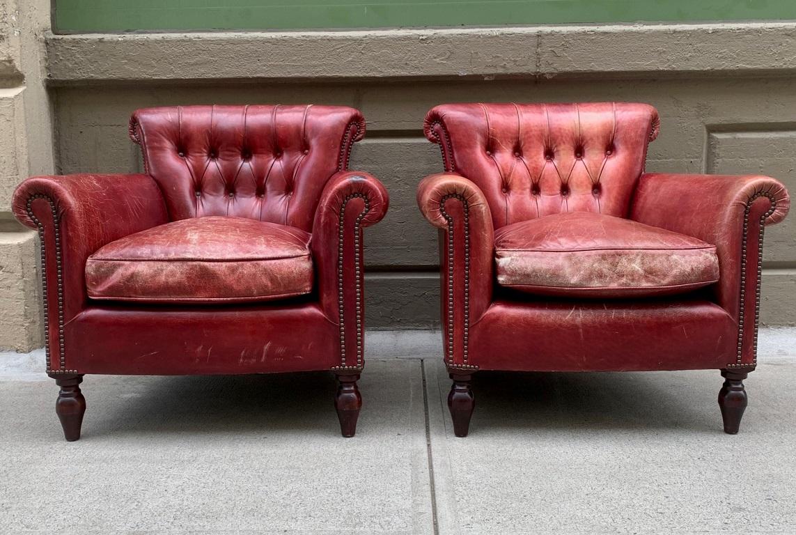Pair of George Smith Lounge club chairs. The chairs are well made with distressed leather upholstery, loose cushioned down filled seats with solid wood legs. Had brass nail head trim to the front arms. Retains the George Smith metal label.