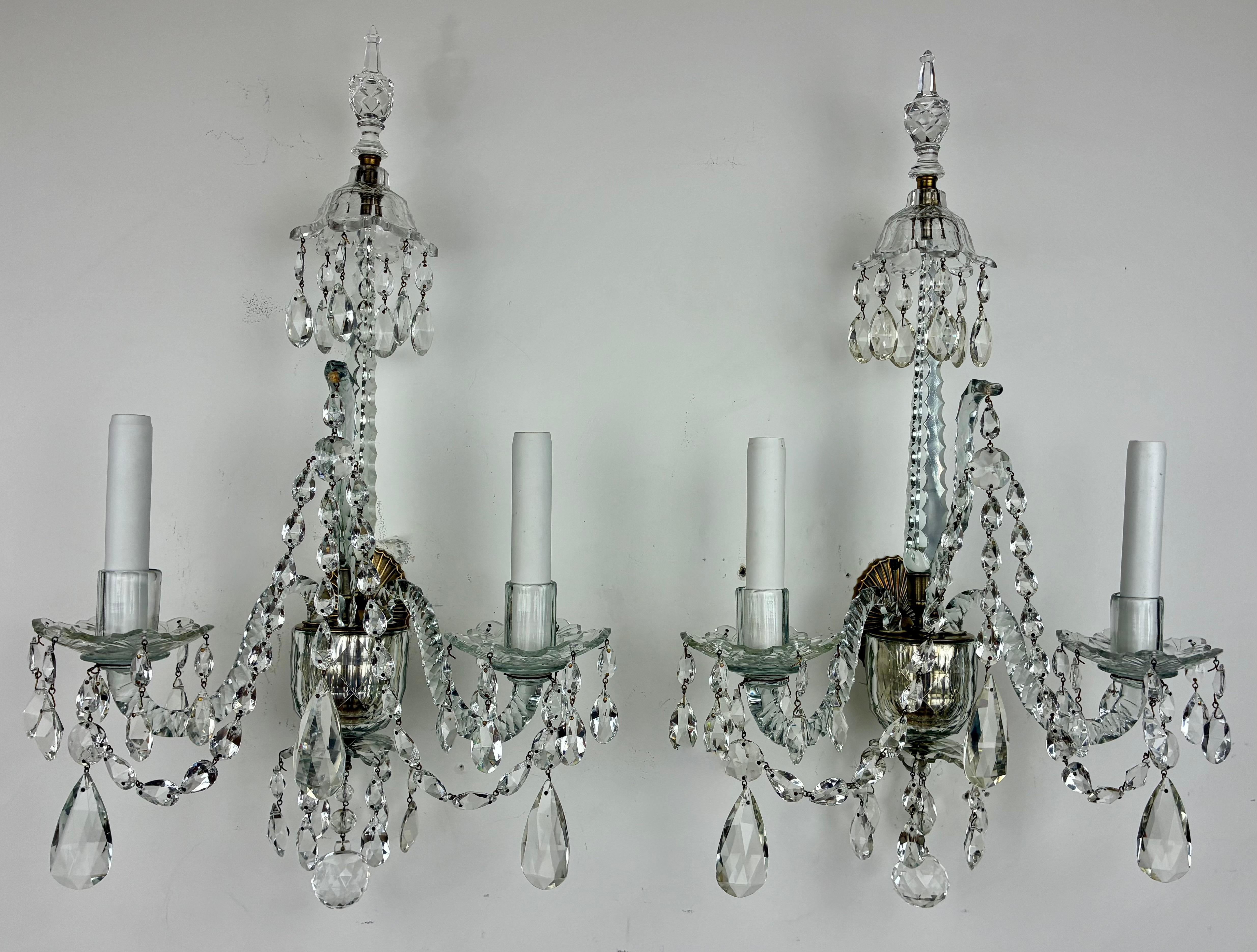 Cette majestueuse paire d'appliques géorgiennes classiques est dans le style de Robert Adams. Ils se caractérisent par des gouttes, des flèches, des bobèches et des fleurons en forme d'urne en cristal taillé et poli à la main. Les plaques arrière en