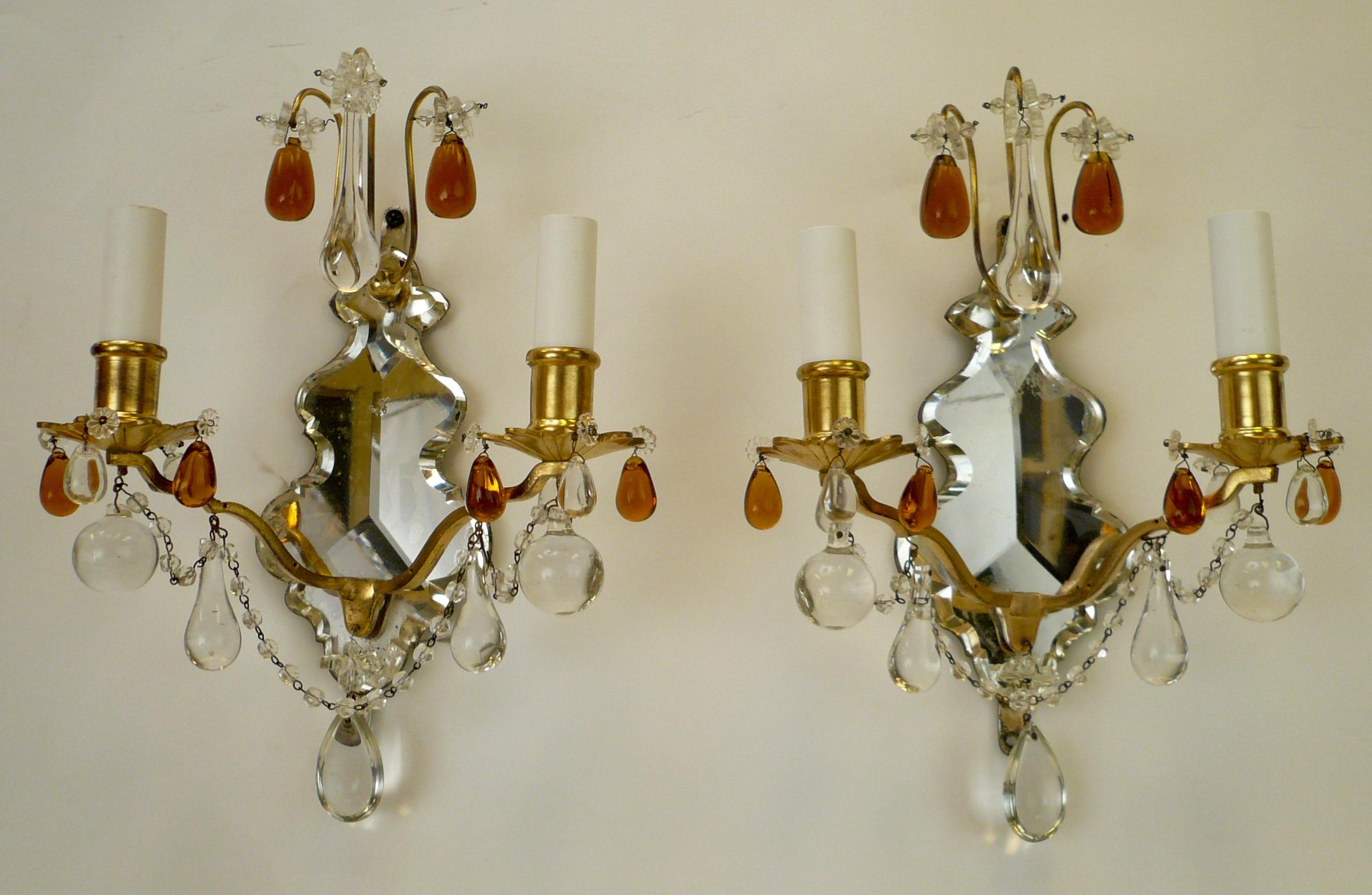 This stylish pair of mirror backed gilt bronze sconces feature clear and amber crystal prisms.