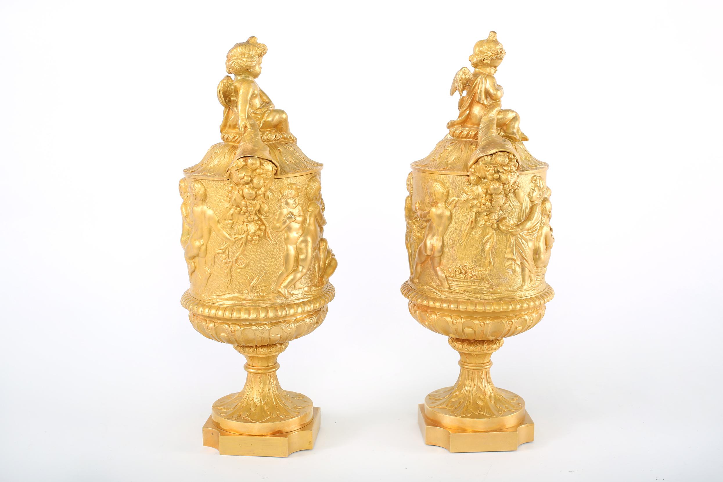 Pair continental gilt bronze covered decorative Urns with exterior design details. Each urn is in great condition. Minor wear consistent with age / use. Each one stands about 15-1/4 inches x 7 inches x 5-3/4 inches.