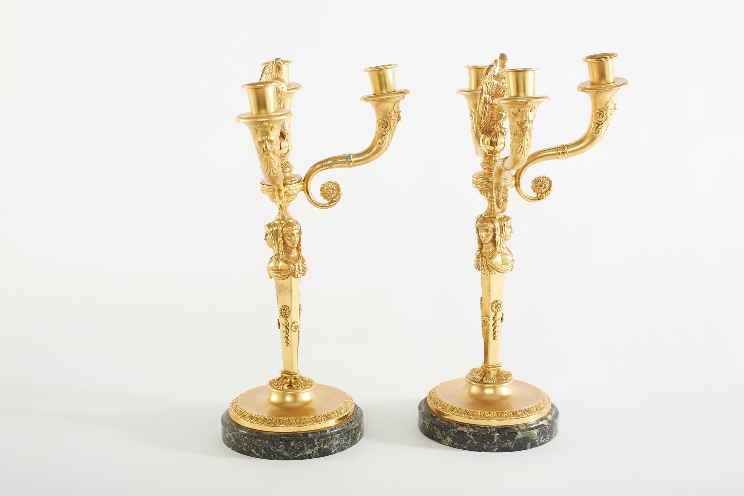 Pair gilt bronze figural three arm candelabra with round marble base and eagle finial top design details. Each candelabra is in great condition. Minor wear consistent with age / use. Each one measure 15 inches tall x 10 inches wide. The base is 6