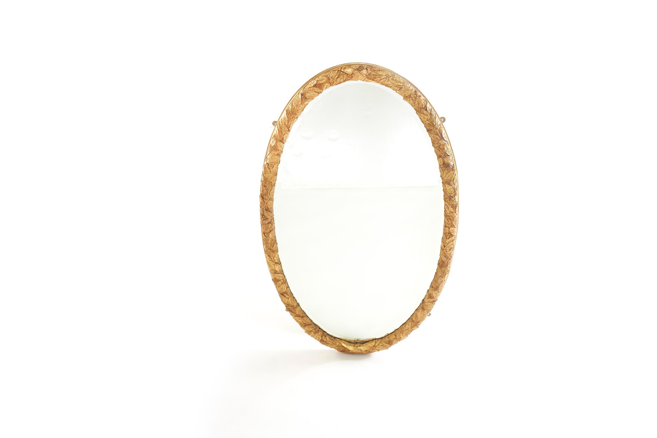 Beautiful pair of gilt wood framed beveled hanging wall mirror in an oval shape with heavily carved wreath branch details motif . The mirror is in good condition. Minor wear / loss to gilt wood frame. The gilt wood frames measure 59 inches high x 32