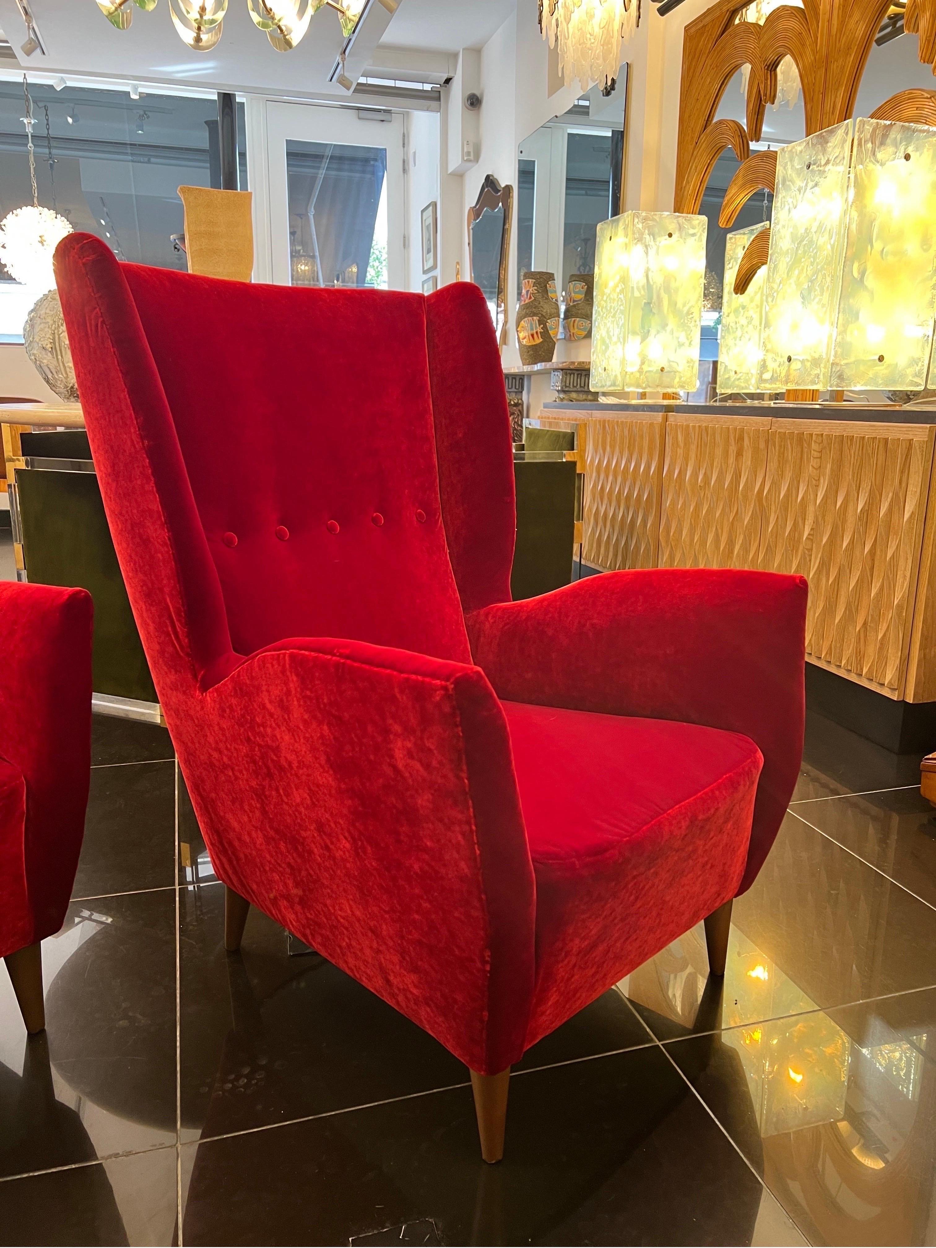 A fantastic pair of Gio ponti wingback armchairs newly upholstered in hand stitched fine Venetian red velvet .