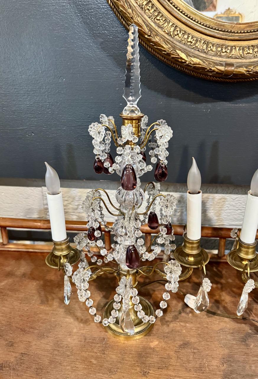 This is a finely detailed small pair of French Bronze Girandoles that date to the beginning of the 20th century. The numerous swags are composed of cut crystal beads. The swags are suspended on purple grape pendants. The finial is a faceted hand cut