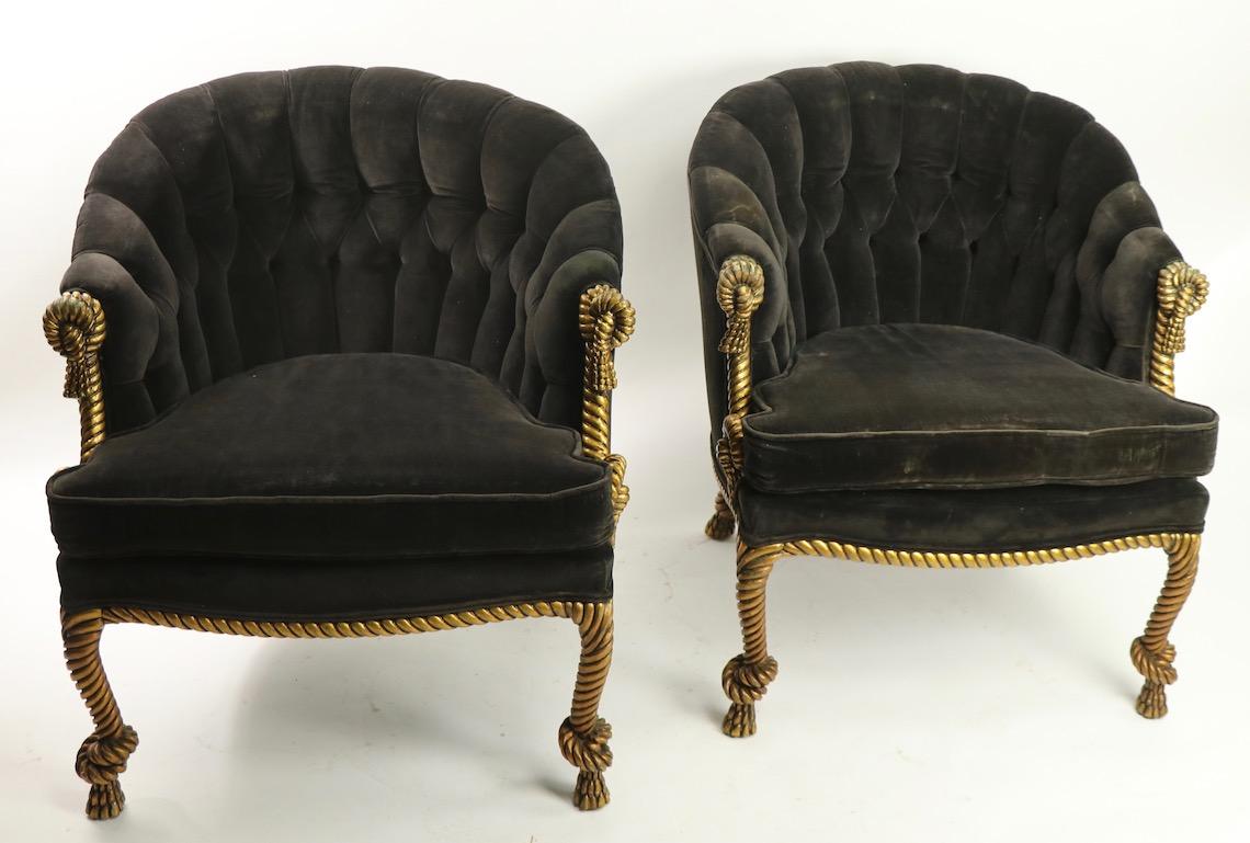Chic and stylish pair of tub chairs having upholstered seats and backs with extraordinary carved wood gold gilt decorated legs and carved decorative tassels. The gilt and carved wood trim is in good condition, showing only light cosmetic wear normal