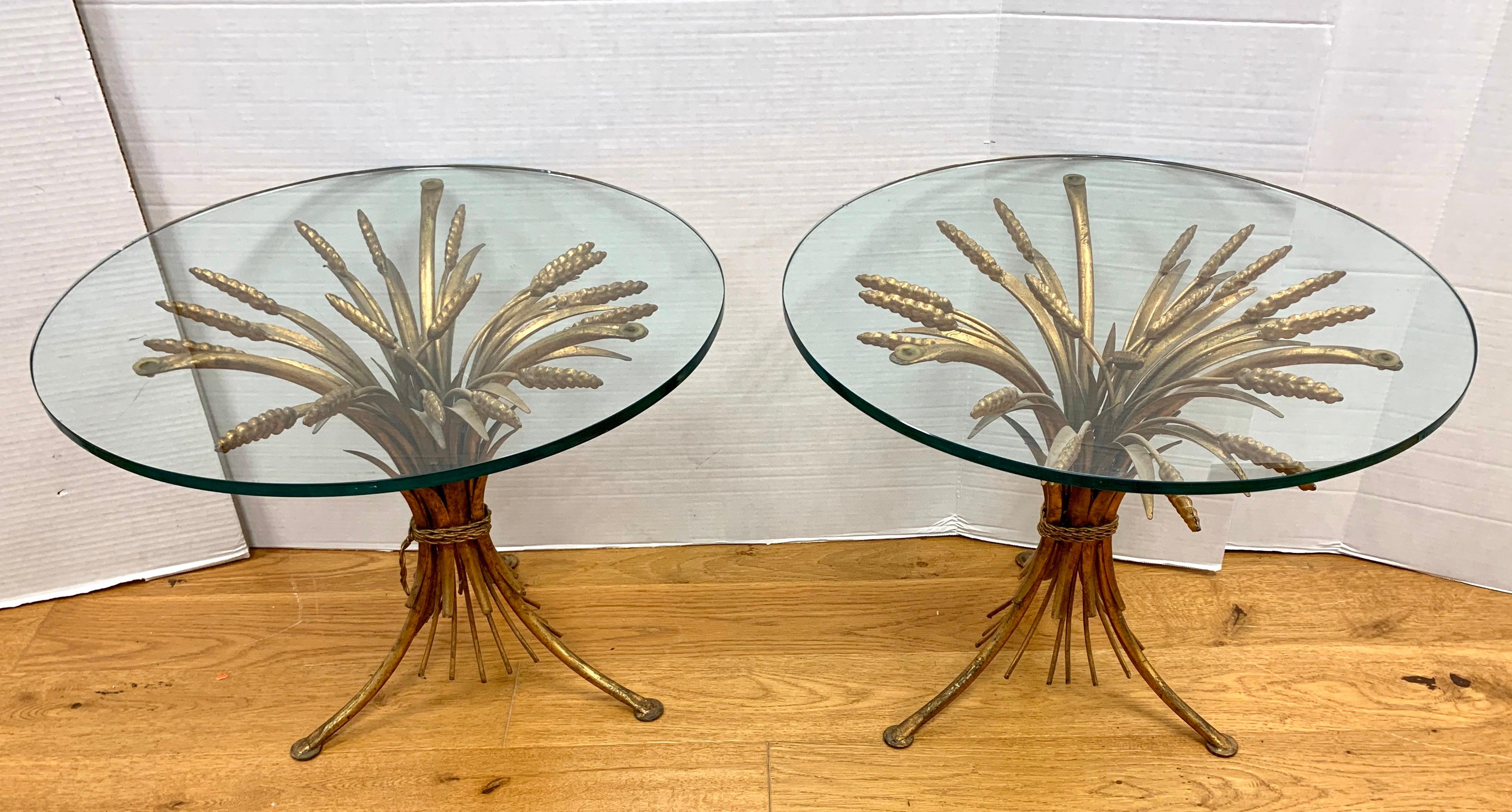 A pair of tables with wheat sheaf base, made of gilt metal, and a round glass top. The wheat sheaf table was made famous by Coco Chanel who used wheat motifs throughout her Paris apartment.