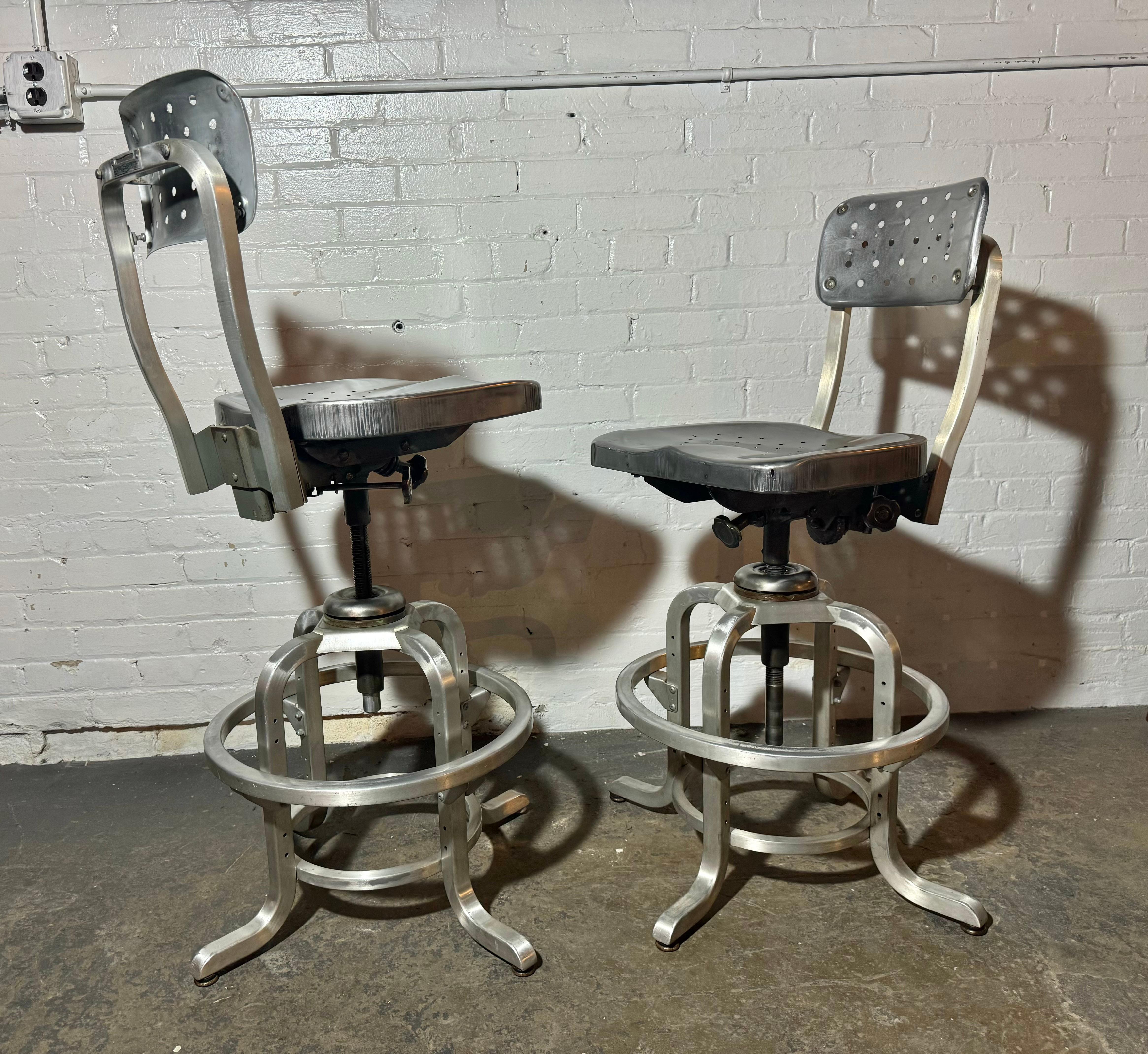 Pareja de taburetes industriales vintage Goodform con asiento perforado y respaldo pivotante. 