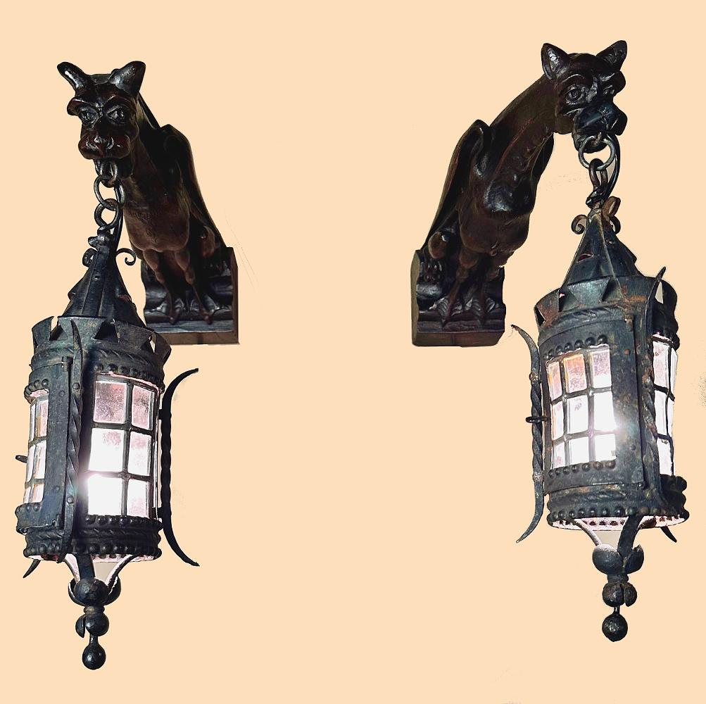 Pair Gothic hand carved Gargoyle Lantern Wall Sconces are perfect for adding a medieval touch to your decor! The timeless Gothic styling of the iron and leaded glass of the lanterns is enhanced by the hand-sculpted gargoyles that project out from