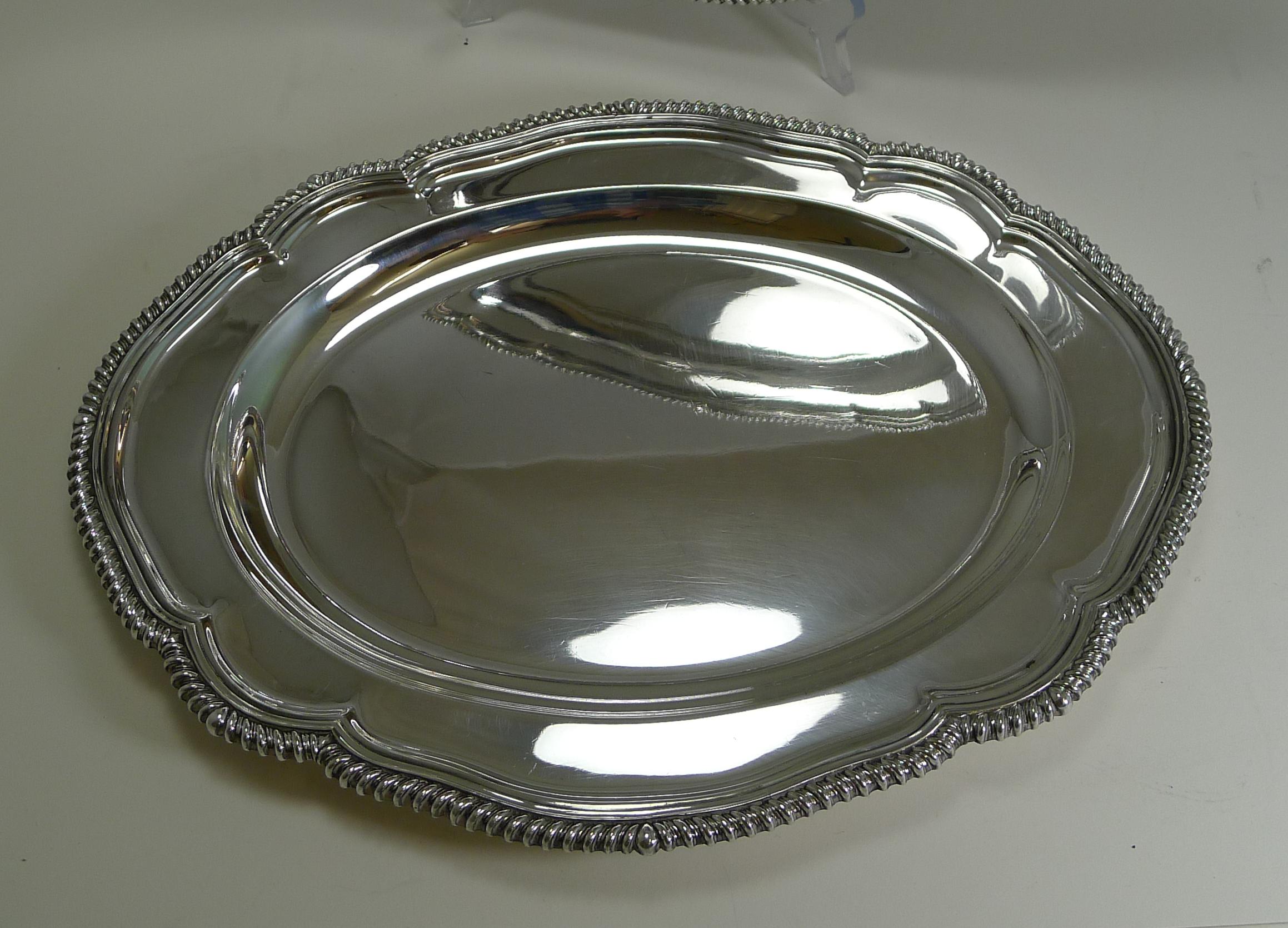 A wonderful pair of graduated serving platters by the top notch silversmith, Elkington and Co.

The shaped platters have a lovely raised border. Each is fully marked on the underside and being Elkington comes with a date letter (Z) allowing us to