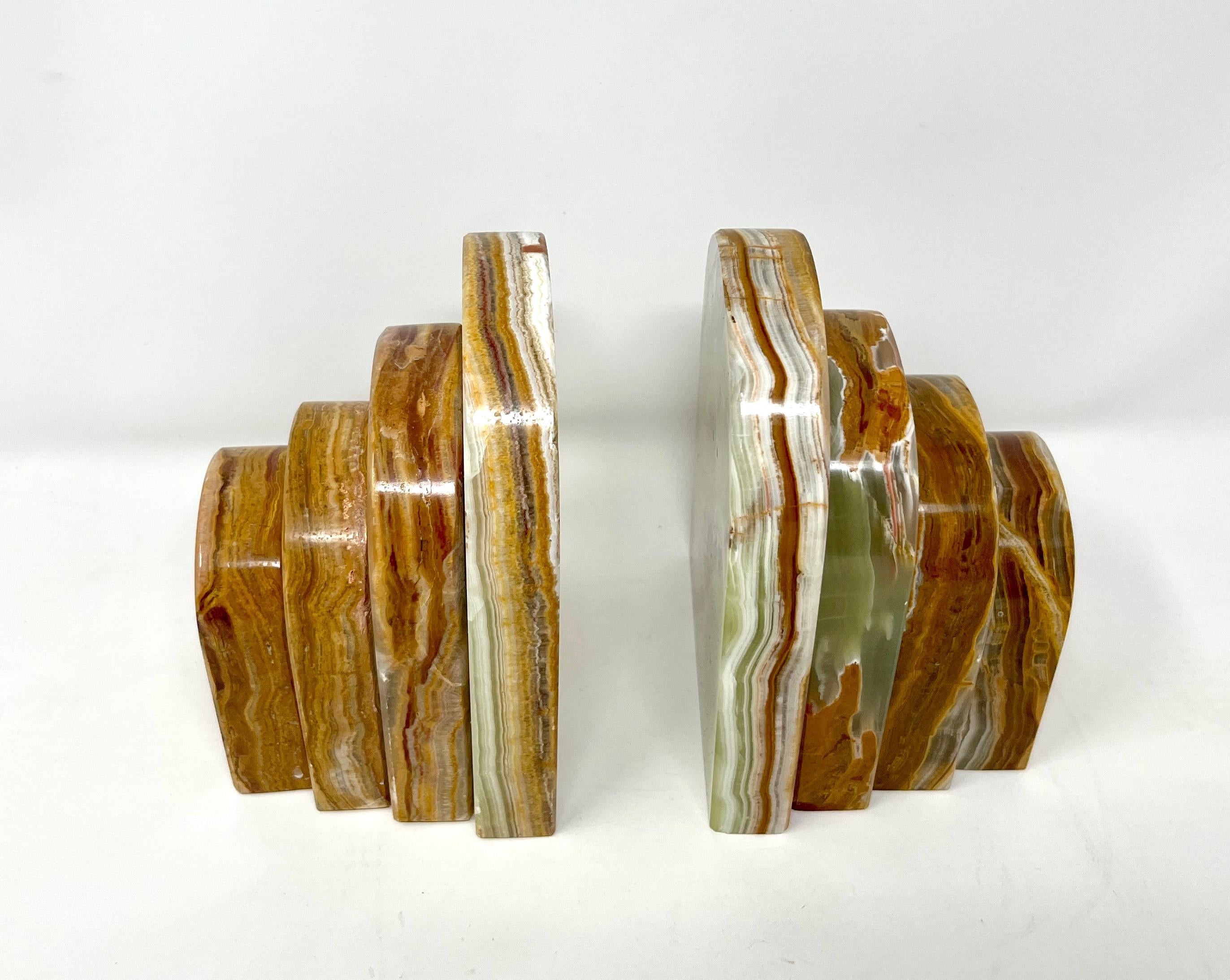 Pair of striking stacked natural stone bookends in richly veined brown and green onyx. A graduated design, reminiscent of the Chrysler Building, allows them to be placed in different configurations. At 4 lbs. each, they are excellent at holding