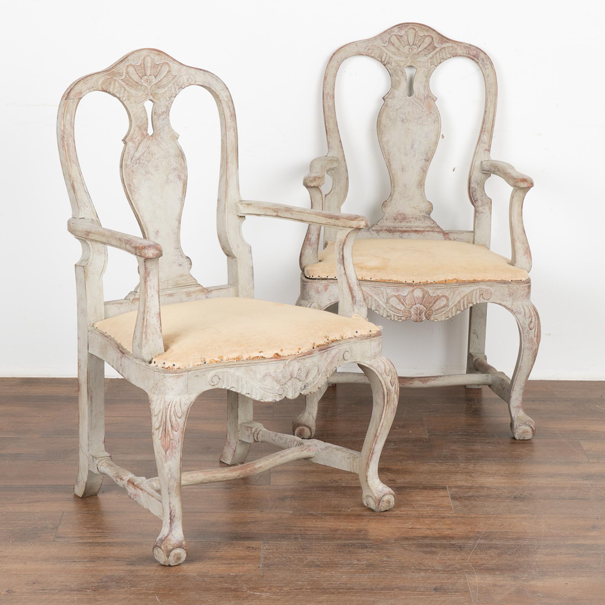 This graceful pair of Swedish Gustavian arm chairs have a wonderfully warm patina thanks to the lovely finish.
These armchairs have been given a newer, professionally painted gray layered finish which is lightly scraped creating a soft contrast