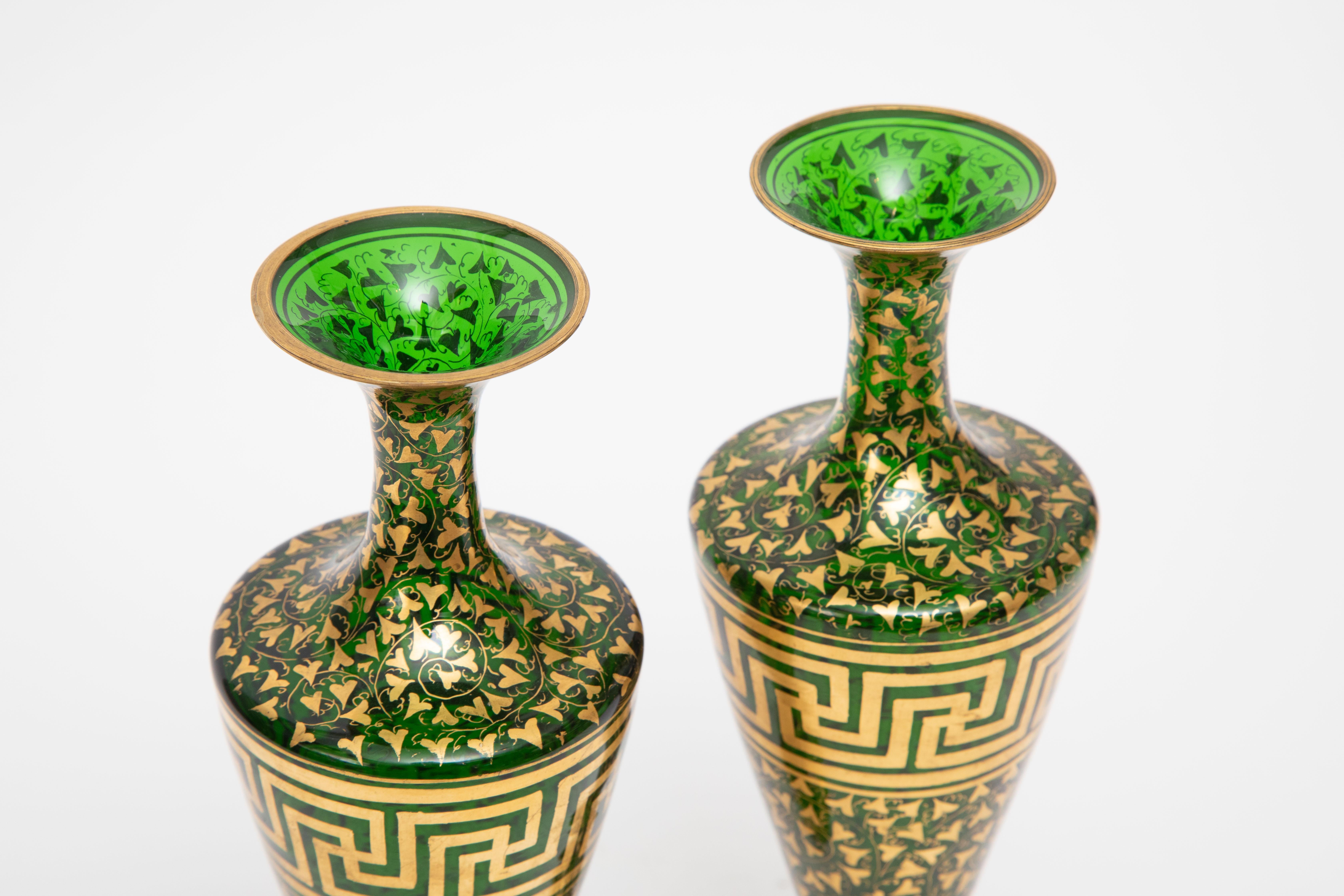 Rich green blown crystal vases featuring 24 karat gold decoration throughout with the central portion having a Greek key design. This pair dates to the last half of the 19th century and we attribute the craftsmanship to Moser. Elongated necks and a
