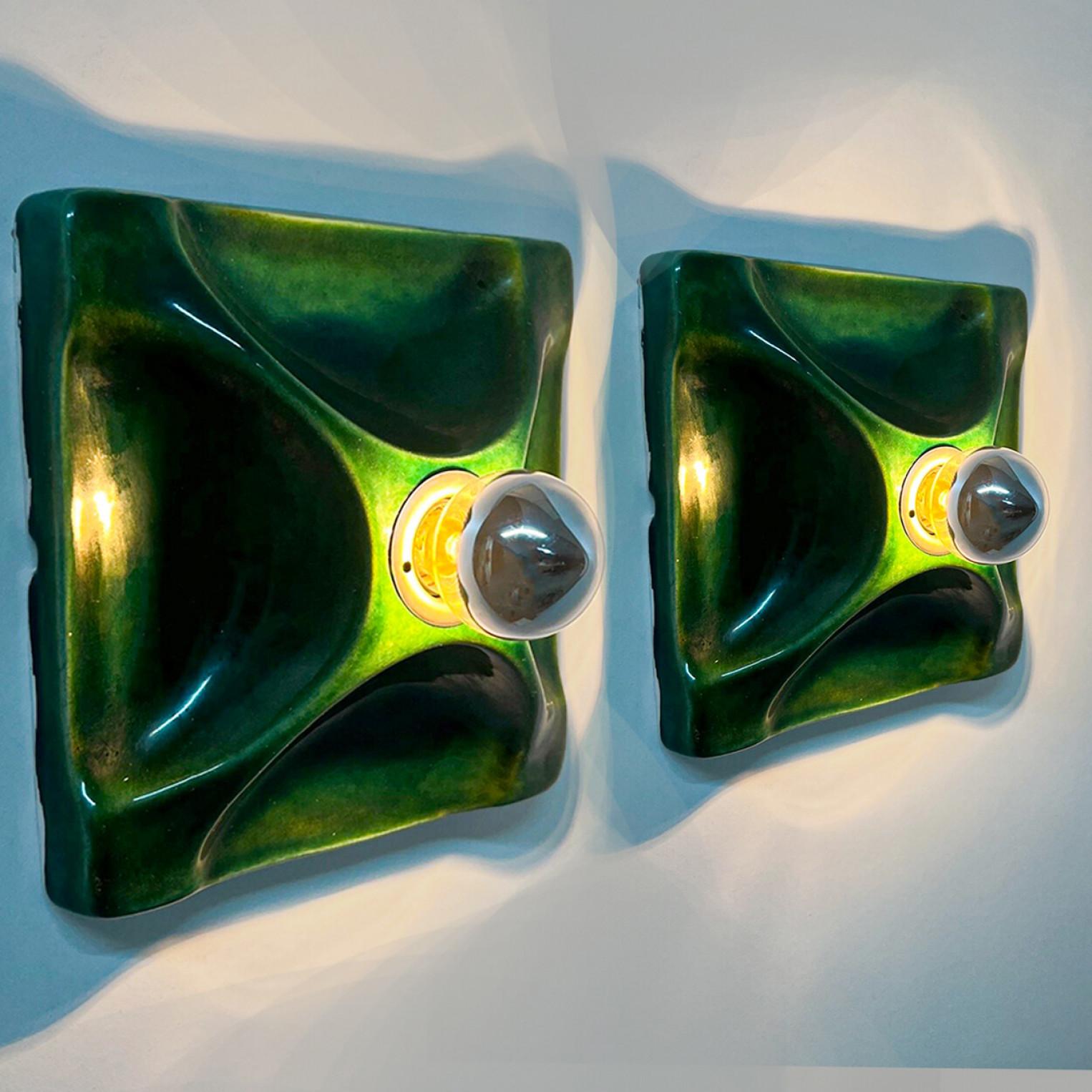 Pair of Green square-shaped ceramic wall lights/flush mounts  in Fat Lava style.

Manufactured by in Germany in the 1970s. The base of the light is square and there is a beautiful ceramic cross on top of that.

This lights have a unusual shape. This