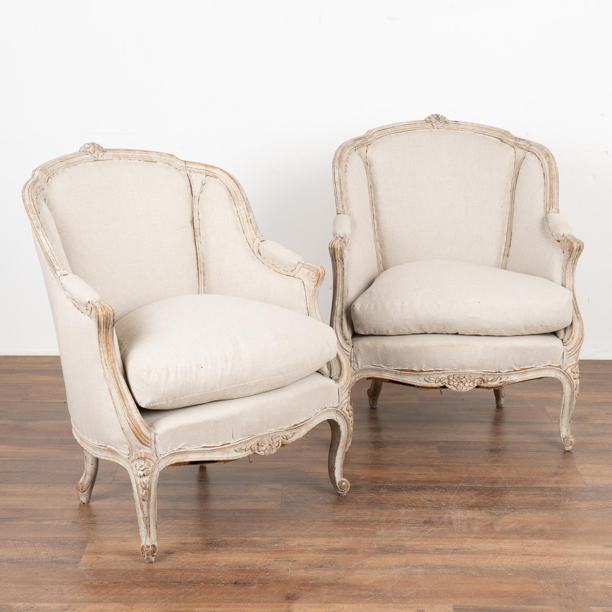 Pair, attractive Swedish country Gustavian white painted barrel back arm chairs.
Carved floral details along top and skirt, resting on curved cabriolet feet which combine to create the romantic appeal of this pair. 
The white painted finish is