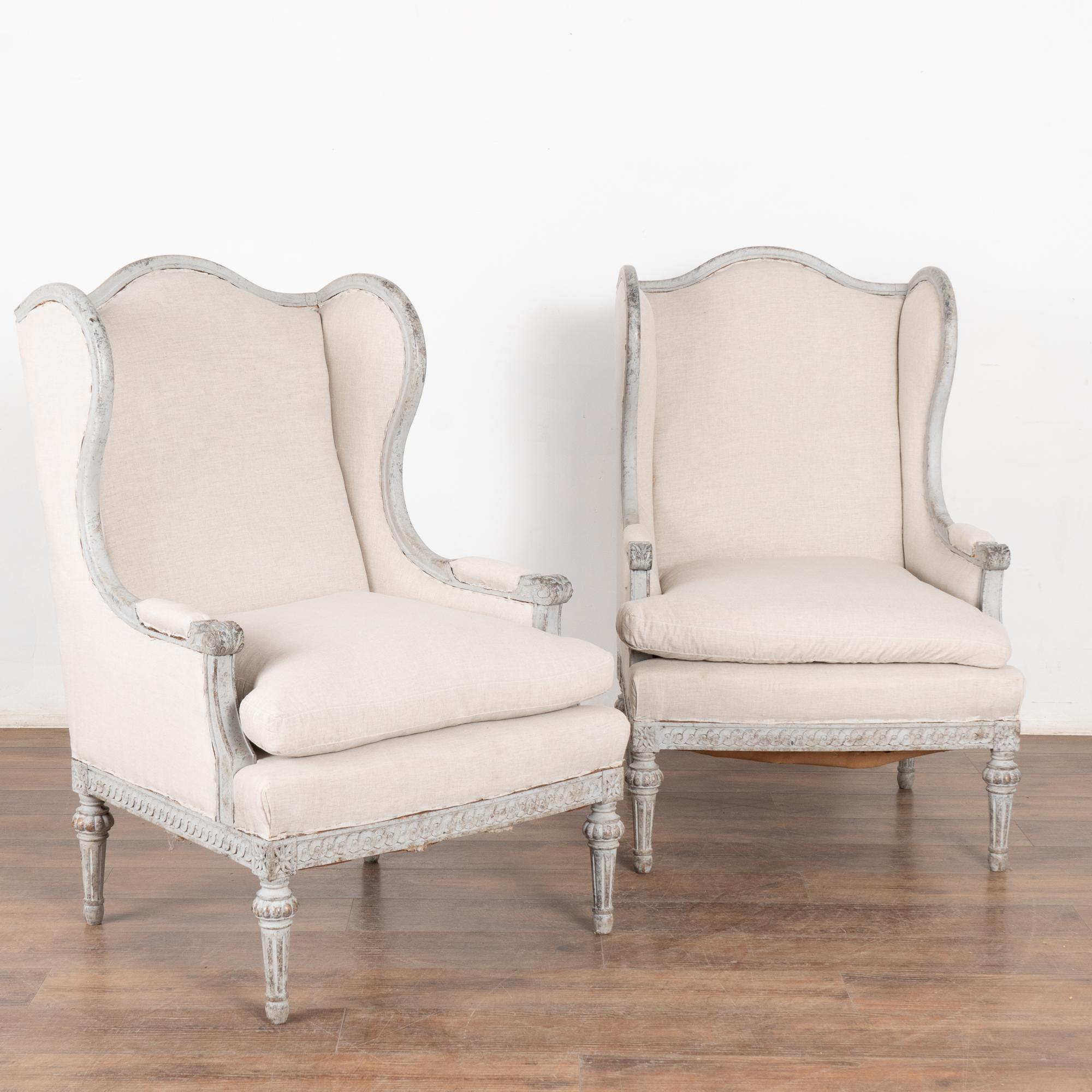 Graceful with a romantic air, this pair of Gustavian style wingback armchairs have delicate carving along the skirt skirt and rest on turned fluted legs.
This pair of armchairs are restored, stable and ready to use. The newer professionally applied