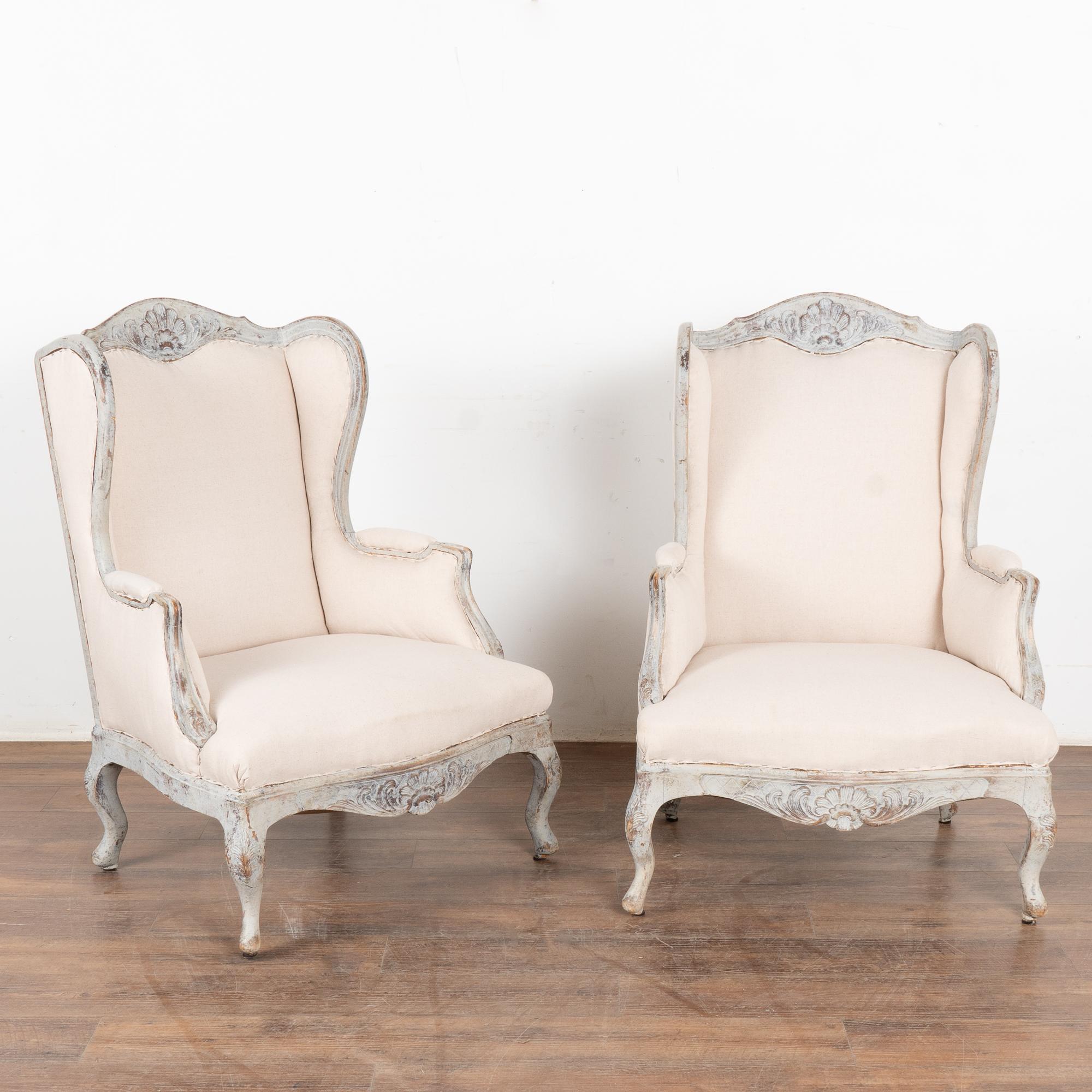Gracieuse et romantique, cette paire de fauteuils à oreilles de style gustavien présente de délicates sculptures le long du cadre, de la couronne et de la jupe, et repose sur des pieds en cabriolet.
Cette paire de fauteuils est restaurée, stable et