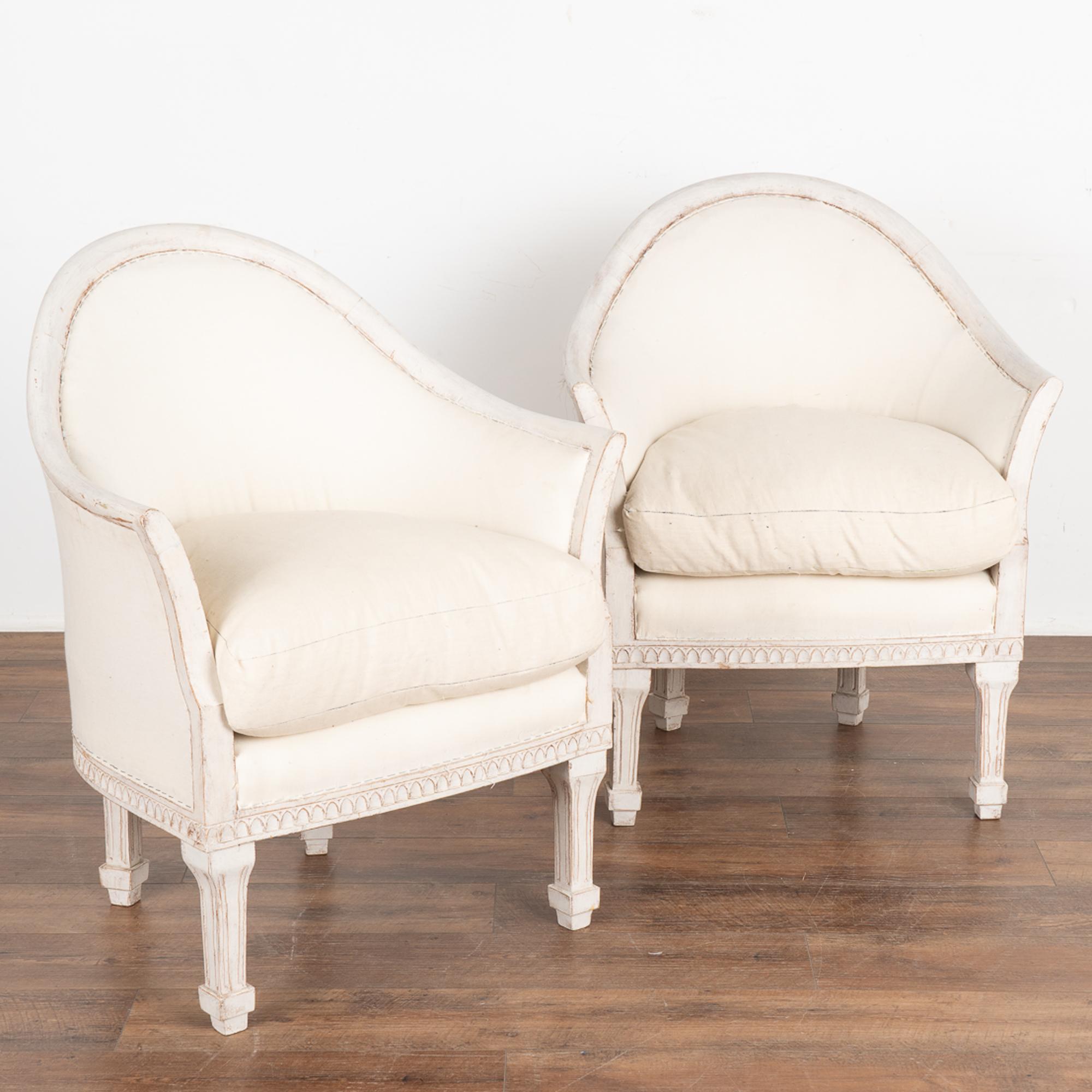 This pair of Swedish arm chairs have a gently curved barrel back and slightly turned out arms, adding to the graceful appeal of each.
Fluted legs and decorative carving embellish the skirt. 
The newer professionally applied white layered painted