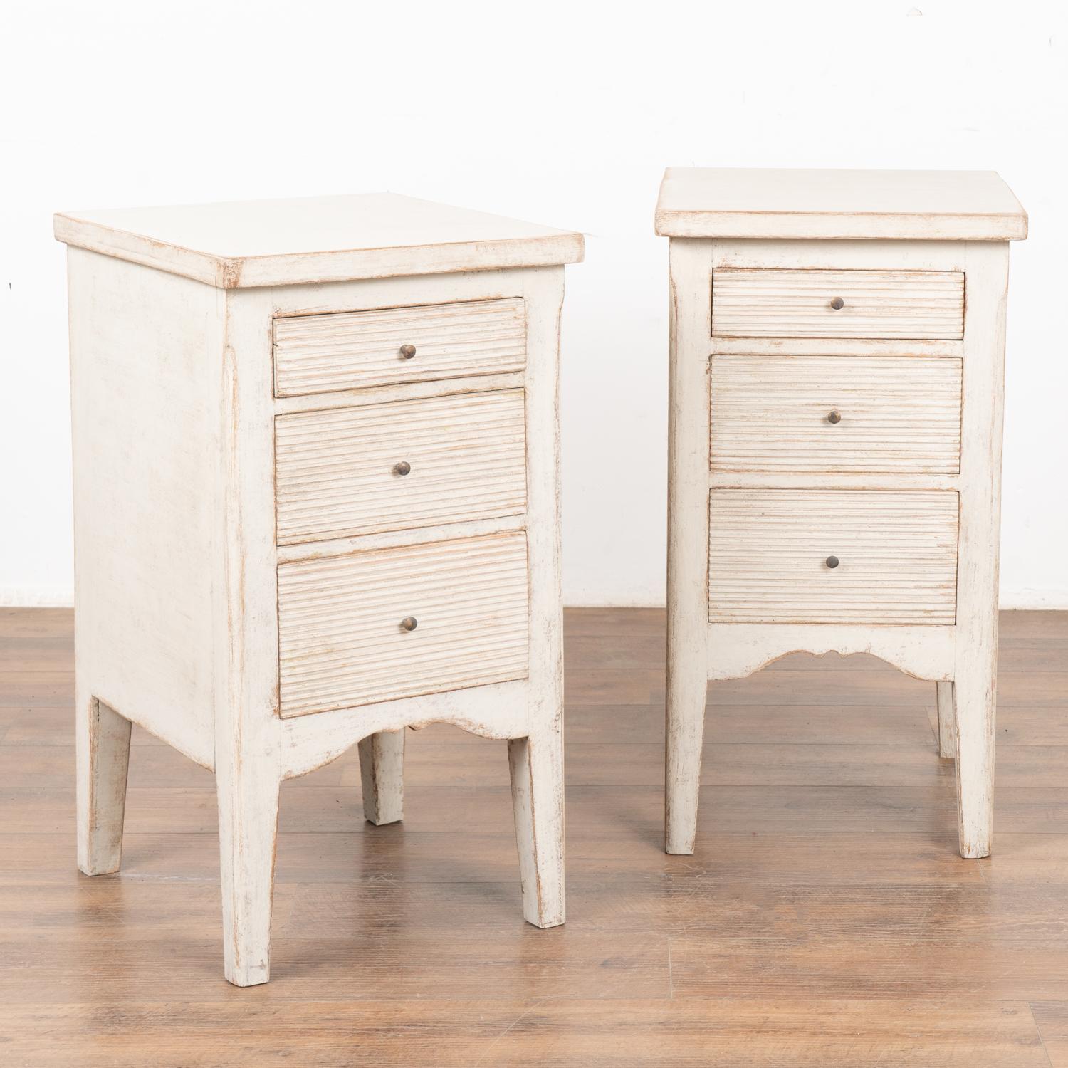 Pair, Gustavian style small pine chest of drawers with fluted drawers perfect to use as nightstands or small side tables. 
Note the top is hinged, revealing hidden storage within. The three drawers each have two brass pulls to open.
The newer,