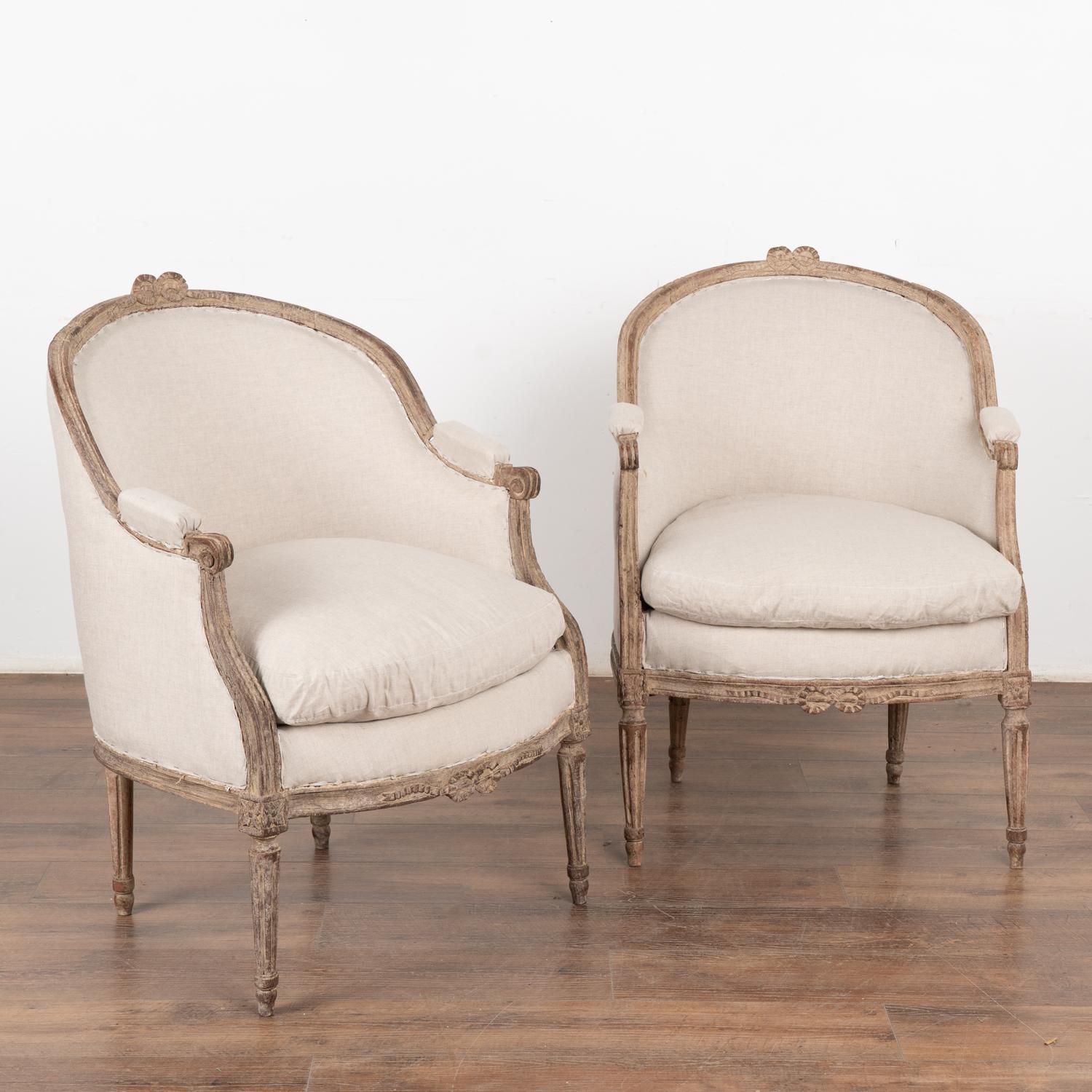 Pair, attractive Swedish country Gustavian style arm chairs with gently curved barrel back and carved ribbon/bow adorning the back and skirt. Turned fluted feet.
Newer, professionally applied layered antique white painted finish has been distressed