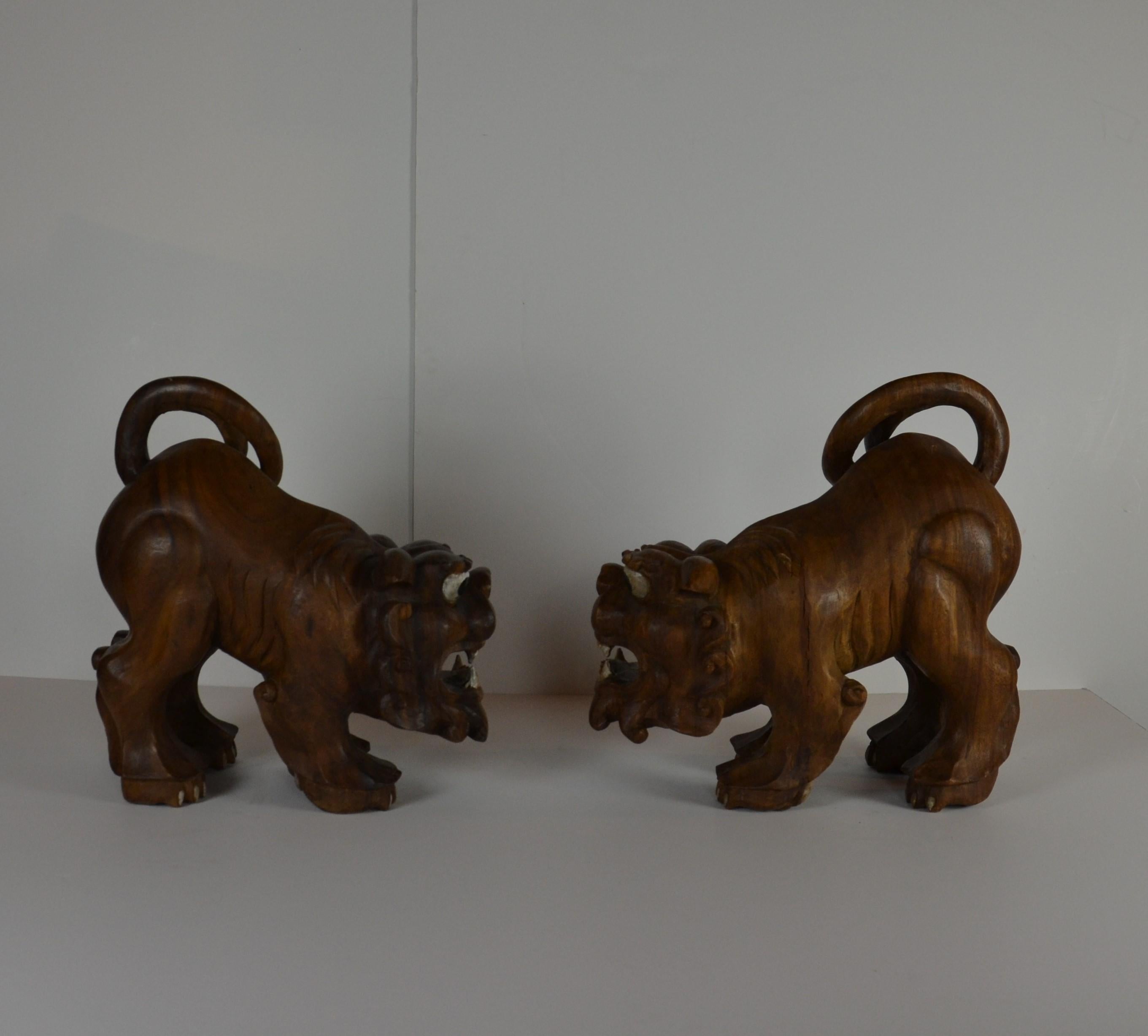 A pair of hand carved rosewood foo dogs or temple guards. The eyes, and teeth are painted.