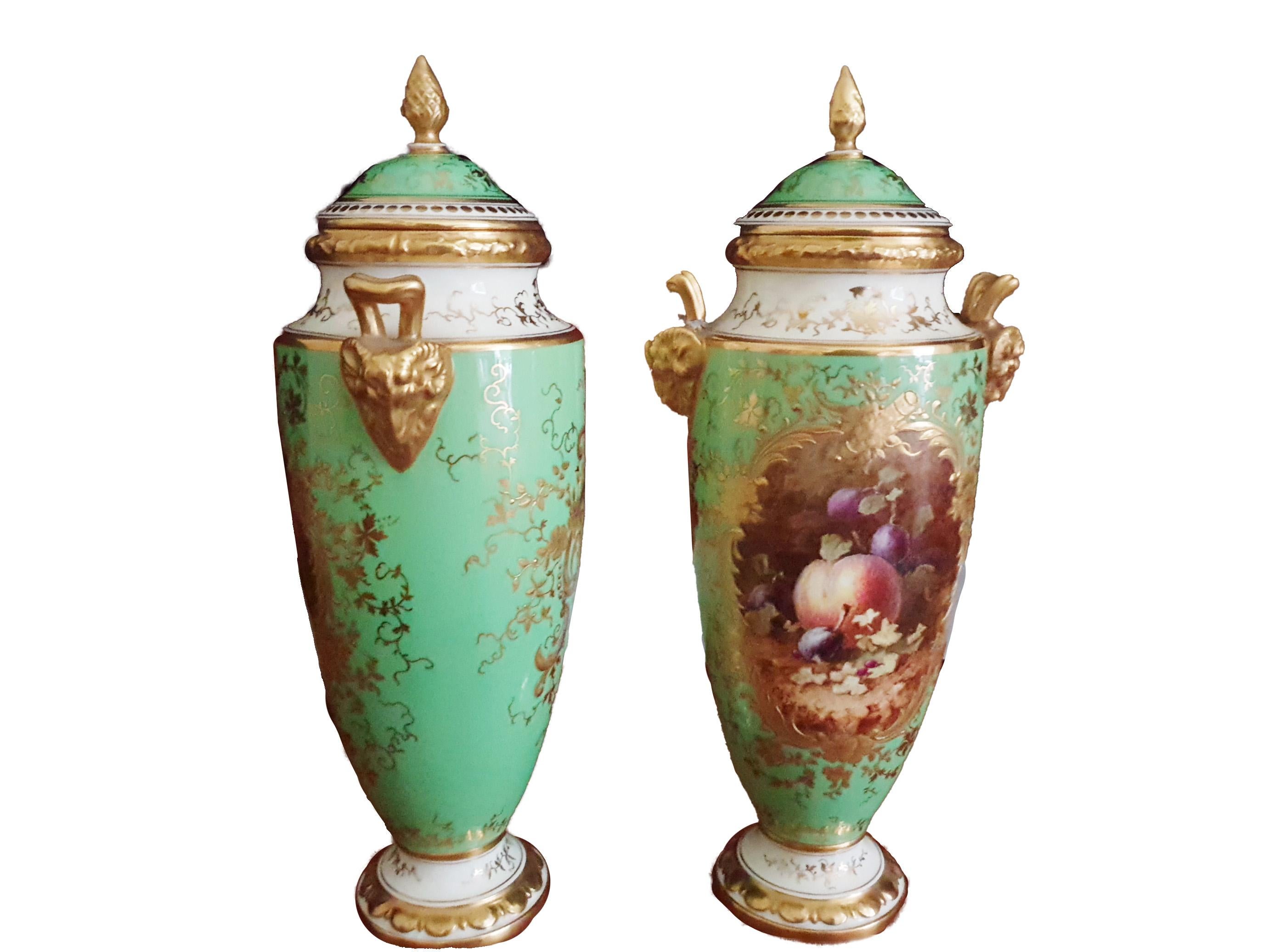 A  impressive pair of Coalport porcelain vases and covers with gilt pine cone finials, crafted in early 20th Century, finely handpainted and signed by Frederick H. Chivers.
Each ovoid body is painted within a scrolling gilt cartouche filled with