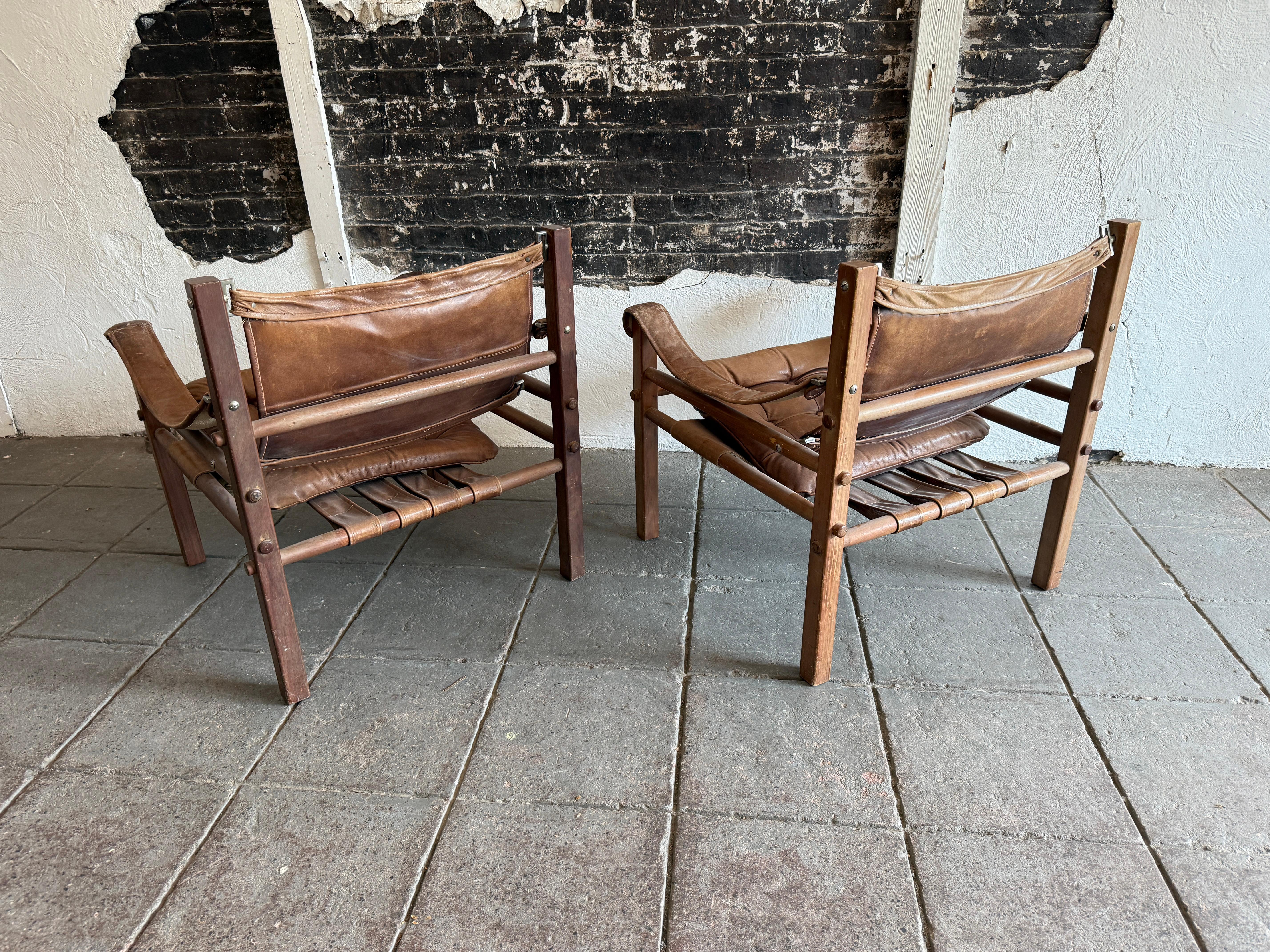Pareja de sillones safari de cuero marrón de mediados de siglo con pátina mediados del siglo XX en venta
