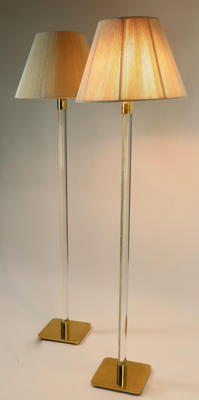 Paire de lampes sur pied chic et sophistiquées de Hansen. Les lampes ont chacune une tige verticale en verre massif avec une base carrée et un chapeau en laiton. Ils sont dotés de l'interrupteur à anneau gris caractéristique situé en haut pour