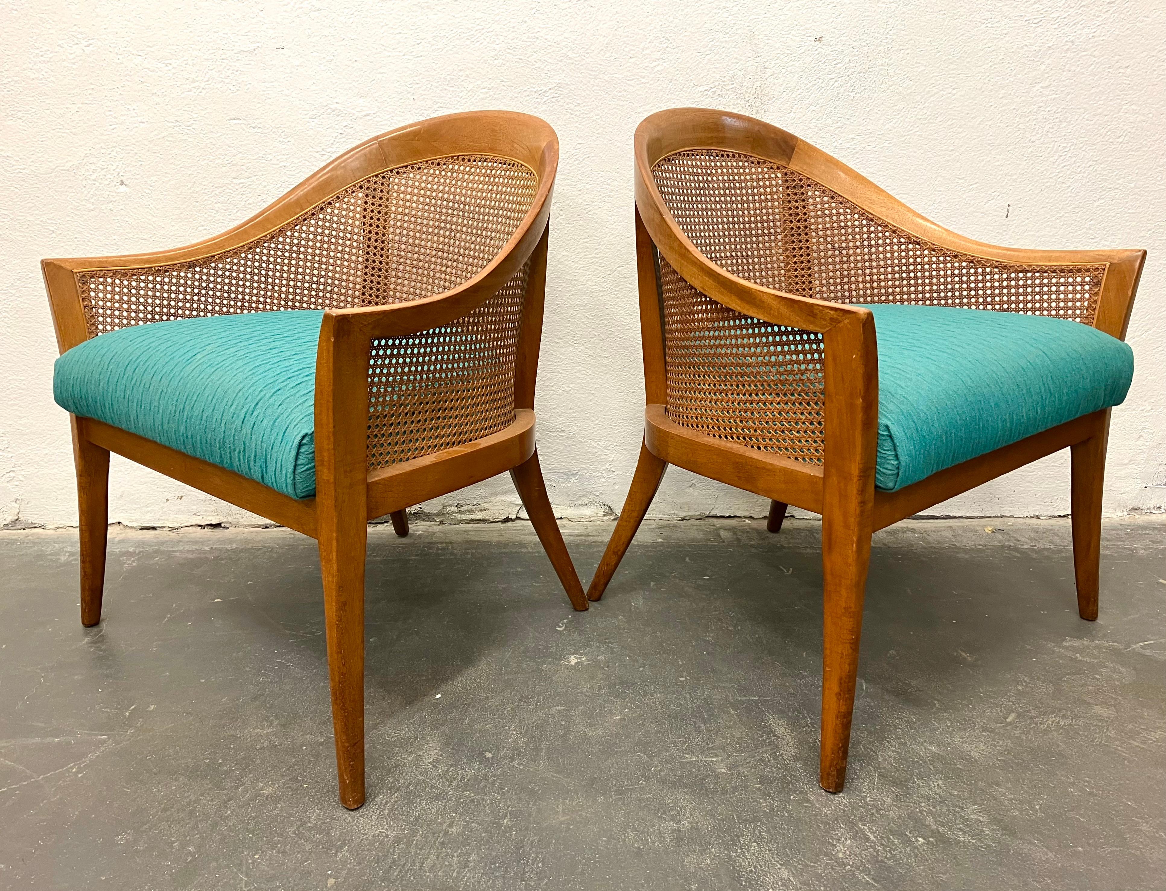 Elegant pair of lounge chairs in bleached mahogany with caned sides. The tapered and tailored design easily works in both traditional and ultra-modern interiors.
