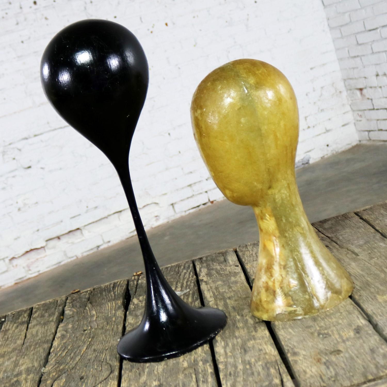 Awesome pair of Mid-Century Modern hat display stands, or wig display stands in fiberglass. One black balloon shaped on tulip base style tall stand and the other tan and more like a stylized mannequin head. Very sculptural and in wonderful vintage