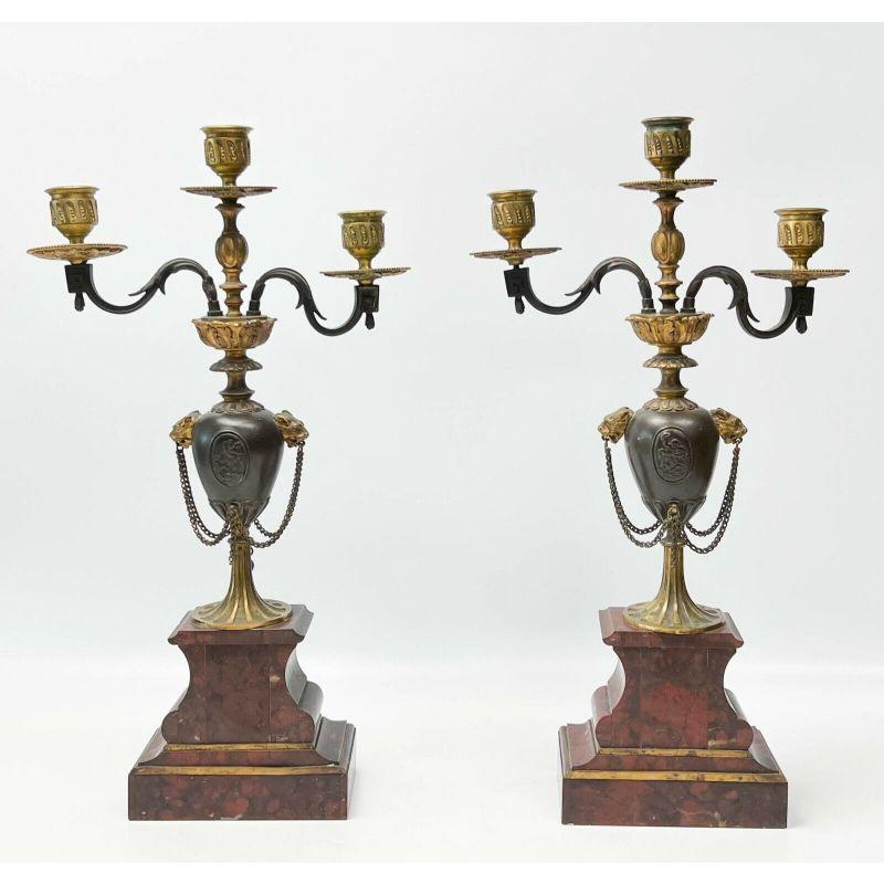 Pair Henri Picard French rouge marble gilt & patinated bronze candelabras, 19th century.

19th century. Red marble bases, bronze stem with a medallion of low relief putti to either side, lion's heads holding chains. Foliate arms, gilt bronze