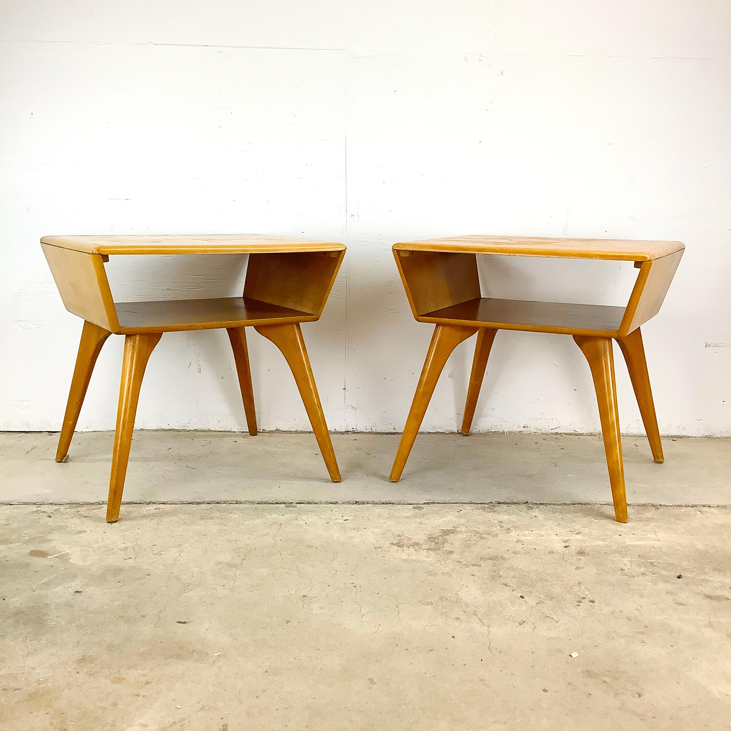 Elevate your home decor with this pair of mid-century end tables by Heywood-Wakefield, a stunning example of classic 1950s design. Made from solid wood, these end tables offer both functionality and aesthetic appeal, featuring an open shelf design