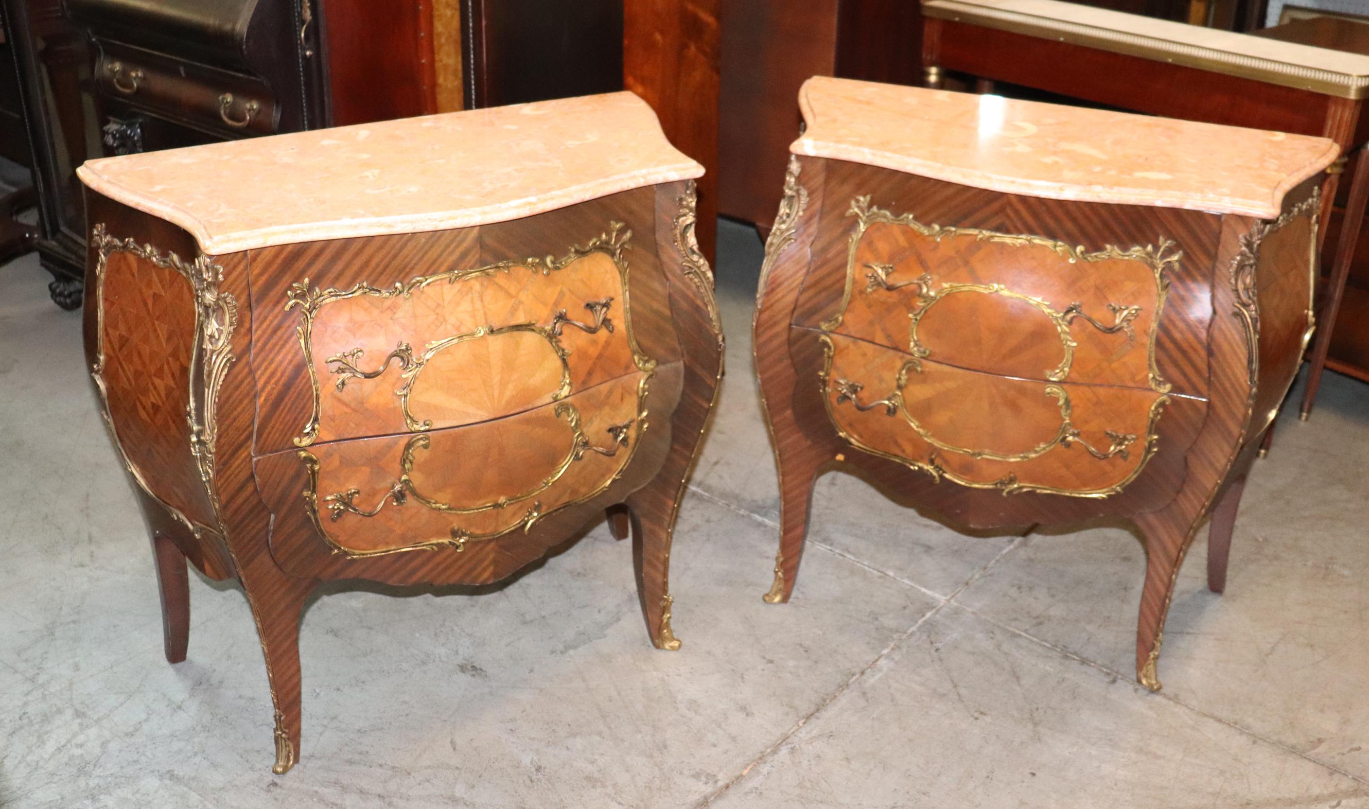 This is a beautiful pair of walnut and mahogany marquetry bombe nightstands with marble tops and fine bronze ormolu. The stands appear better in person but because they are marquetry the lighting makes the designs appear lighter or darker depending