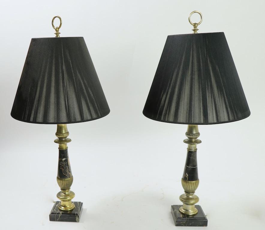 Stunning pair of polished black marble table lamps with decorative cast metal fitments. Both lamps are in very good, original and working condition, the metal elements show cosmetic wear to finish normal and consistent with age. Priced and offered