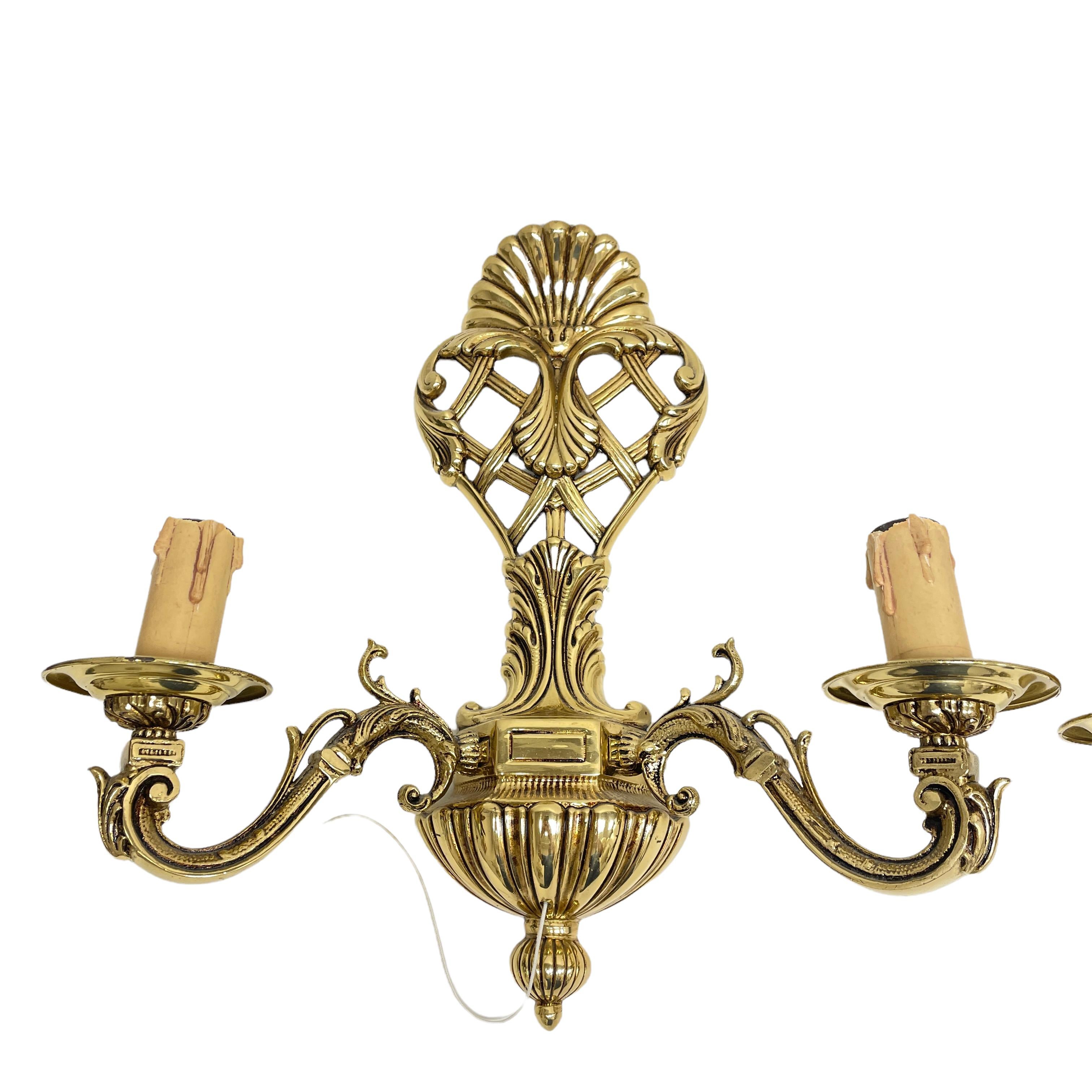 A stunning pair of heavy brass wall sconces. Each consisting of a stylish Hollywood Regency style design. Each fixture requires two European E14 / 110 Volt candelabra bulbs, each bulb up to 40 watts. A nice addition to any room.